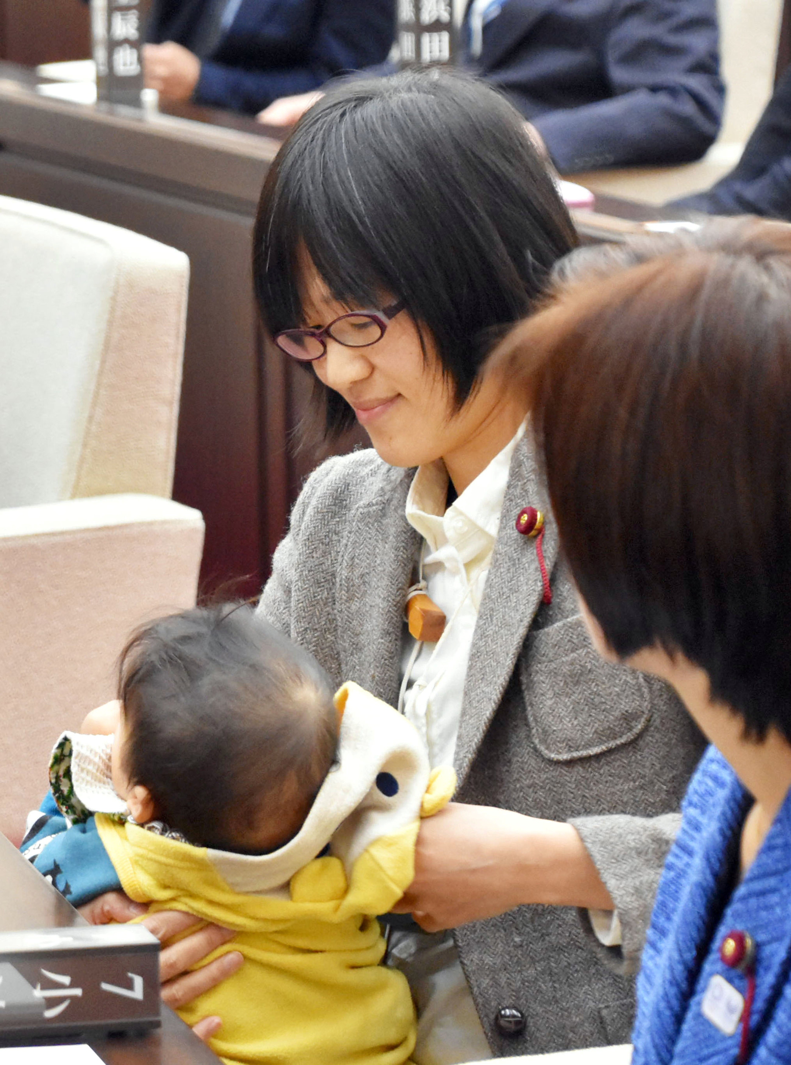 42歲的緒方夕佳在市議會她抱着兒子安靜地坐在前排的議員位置，等待開會。（路透社）