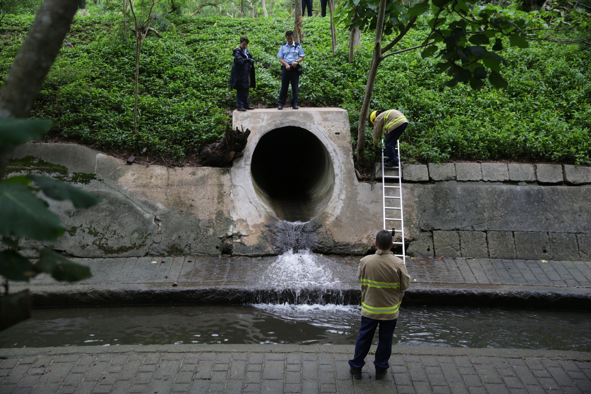 等候漁護署職員期間,警員及消防員一直在渠口守候。 (黃偉民攝) 等候漁護署職員期間,警員及消防員一直在渠口守候。 (黃偉民攝)