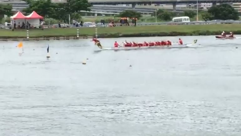 第三艘龍舟緩緩向終點靠近，趴在龍頭處的奪旗手伸長身軀奪旗。（fb群組「爆料公社」短片截圖）
