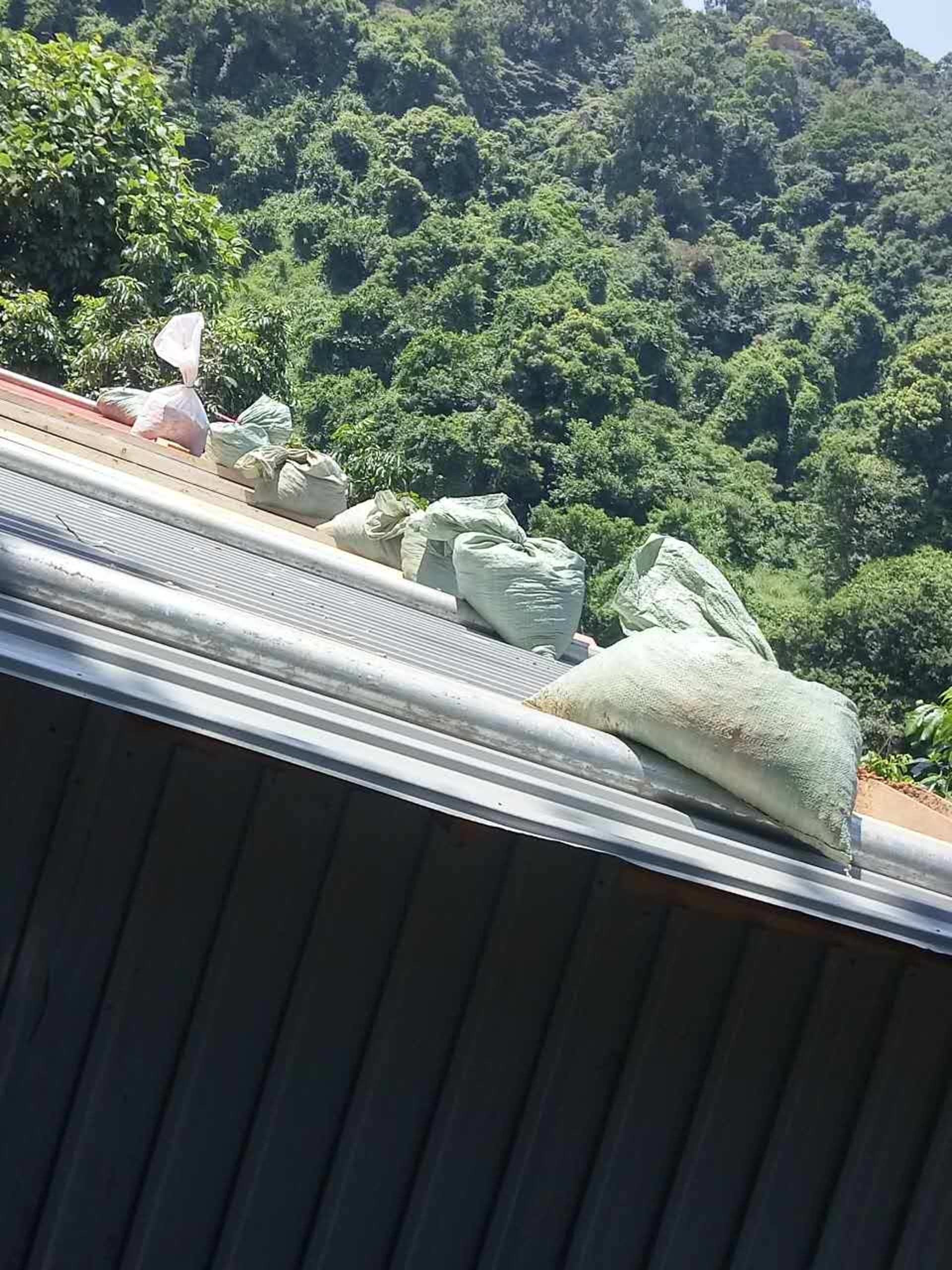 颱風來襲前夕,美虹和萬豪父母在寮屋頂加上沙包,以防被颱風吹塌。 颱風來襲前夕,美虹和萬豪父母在寮屋頂加上沙包,以防被颱風吹塌。