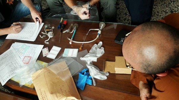 警方搜查開泓法師居住的崇佛寺廂房，檢獲19克安非他命，多種壯陽藥、肛門鬆弛劑、施虐用的軟管、安全套、自慰杯、10多支吸毒工具以及數瓶潤滑液，圖右為開泓法師目睹搜查經過。（台灣警方圖片）