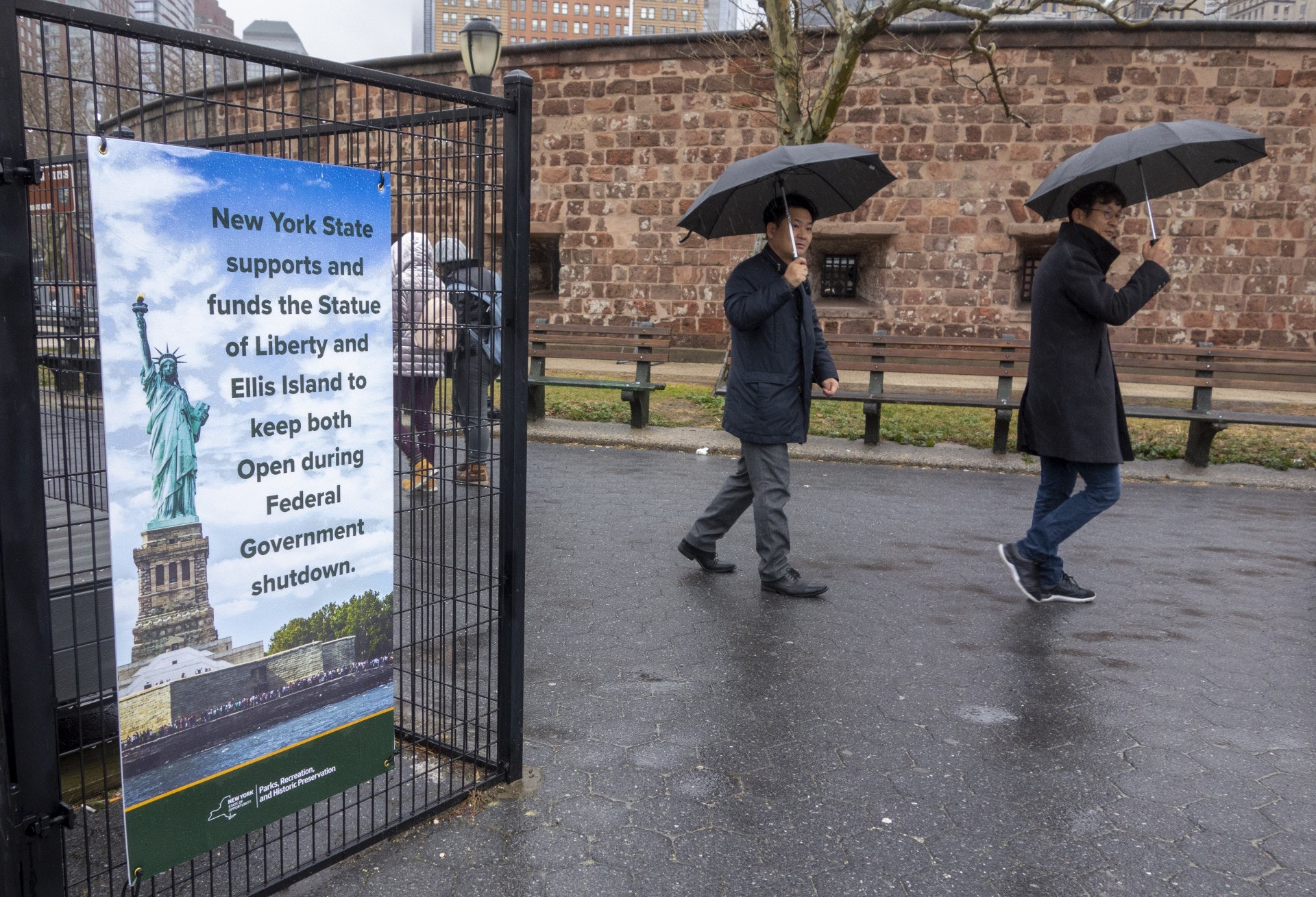 一幅寫着紐約市撥出經費,讓自由女神像維持開放供旅客參觀的海報。(法新社)