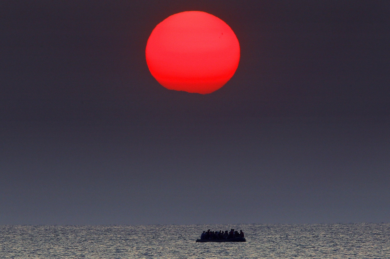 2015年8月11日，愛琴海夕陽下，一艘滿載敘利亞難民的小艇。報道指當時小艇引擎故障，只能隨水飄流。（Yannis Behrakis／路透社）