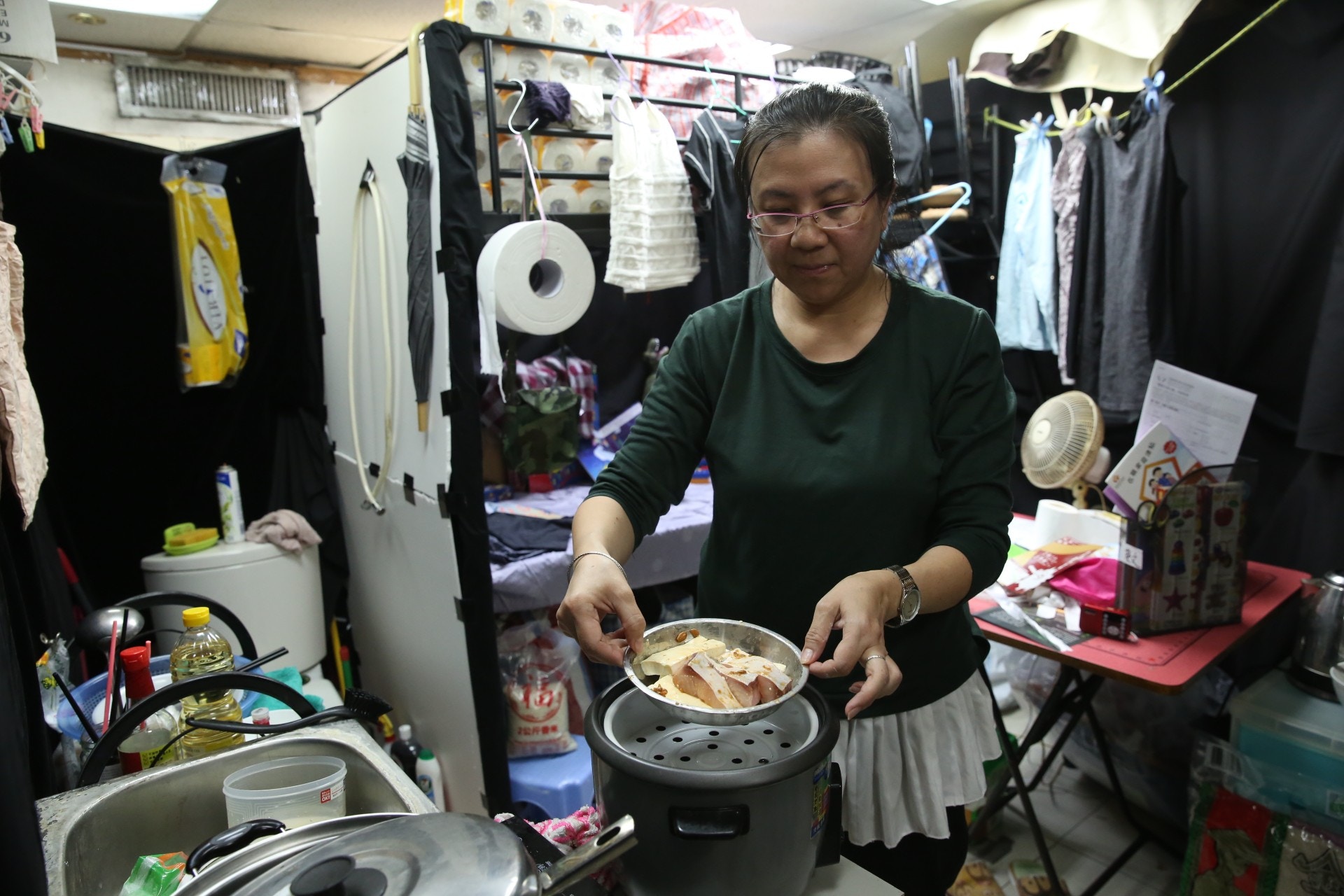 長沙灣劏房戶鄭小姐（Lily）在關注基層住屋聯席搭建的劏房單位內示範日常煮食生活。
