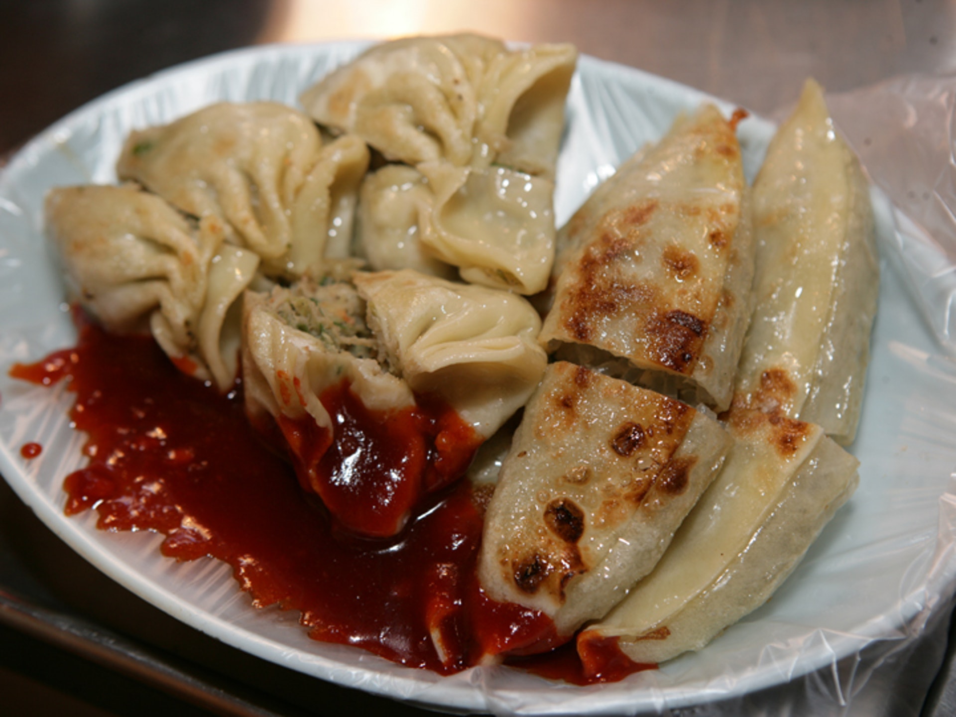 釜山的煎餃是將包好的餃子在鐵板上煎至變成金黃色為止,攤主會把外酥內嫩的煎餃拿剪子剪成一口能吃掉的大小。(韓巢) (韓巢)