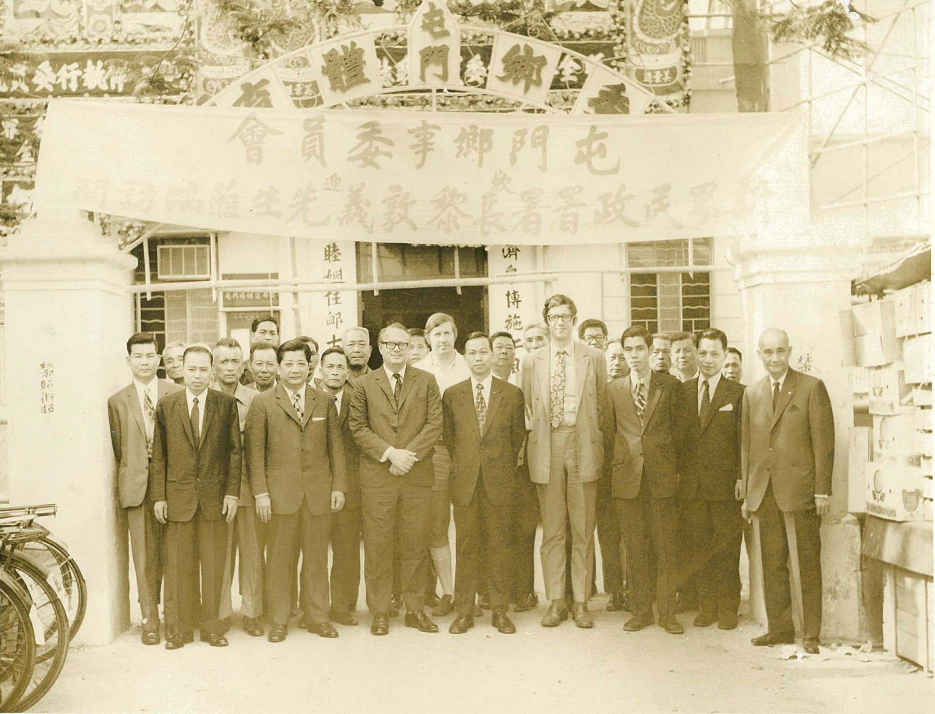 1972年時任新界民政署長黎敦義(前排左三)在立法會宣布實施丁屋政策。圖為70年代他到訪屯門鄉事委員會的合照，他身旁為當時屯門鄉事委員會主席劉皇發(前排左四)。（經民聯網站）