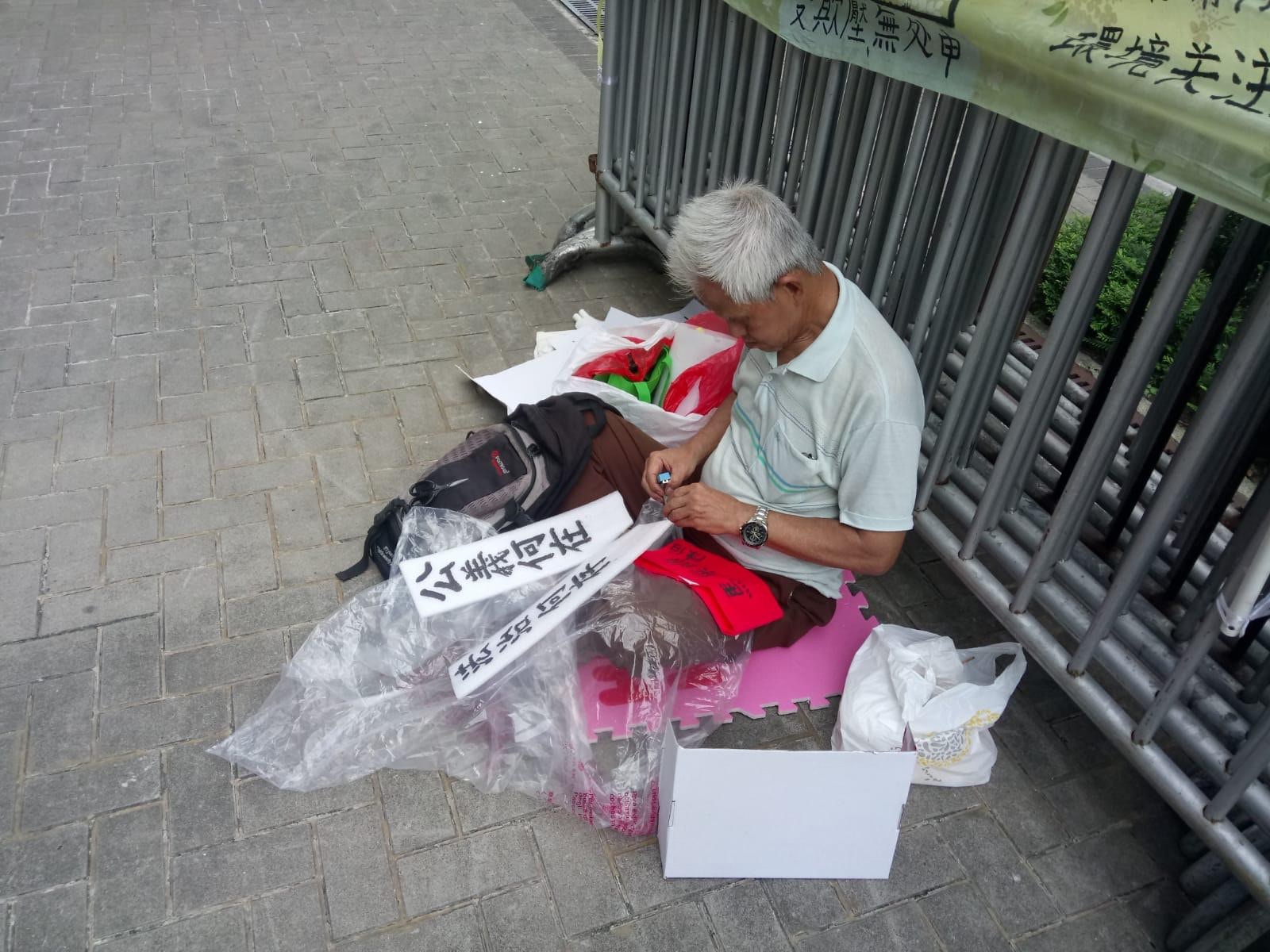 曾居于马屎埔村、逾70岁的陈伯，自周四起于政总外静坐。（受访者提供图片）