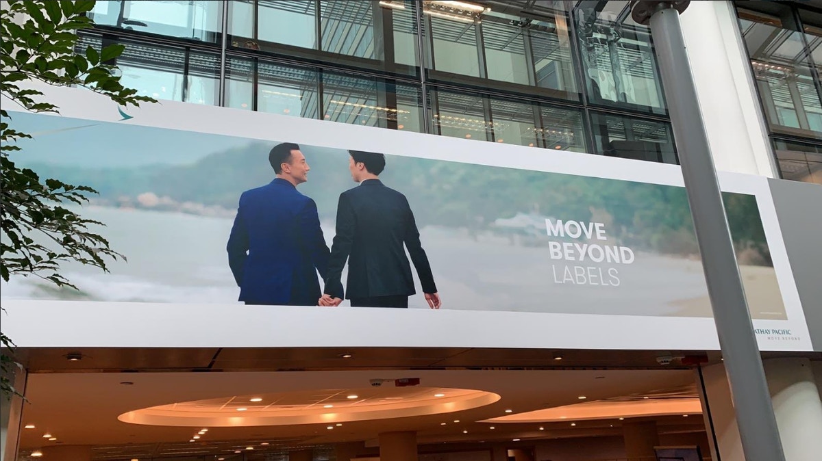 國泰航空「Move Beyond」系列廣告，其中一款海報是兩名男子拖手。國泰將廣告掛在總部國泰城門外。（@CoachBay twitter）
