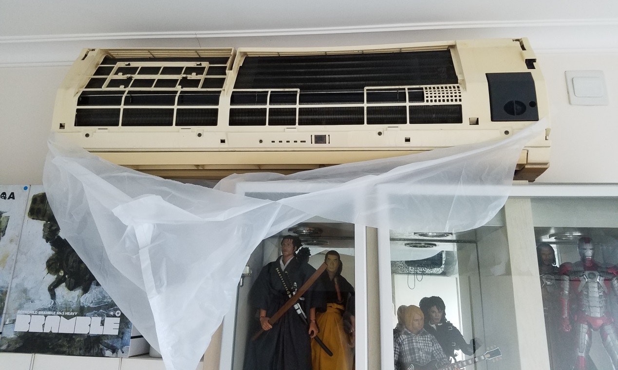 【DIY洗冷氣機】之後用毛巾抹乾淨冷氣機附近,再貼上已經一分為二的垃圾袋,防止污水四濺。(作者提供)