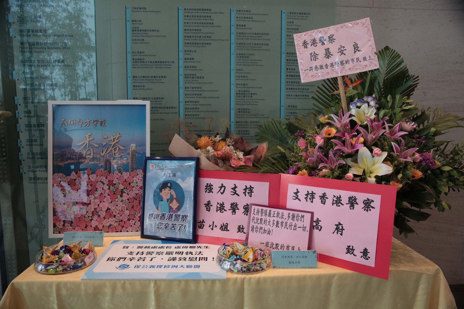 警總3樓大堂放有一張桌子，擺放了由支持警隊的市民及團體送來的鮮花、標語等，而警總的「人事服務及職員關係科」則放了兩盤糖供職員享用，並配上「同甘共苦、甘之若飴」的字句。（梁銘康攝）