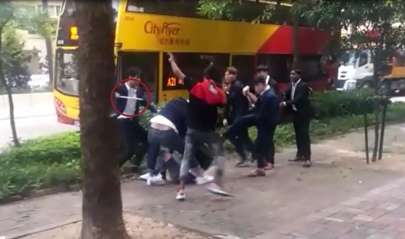 當日代理打架片段可見，有男子手持棍狀物撃打另一名倒地男子。（片段截圖）