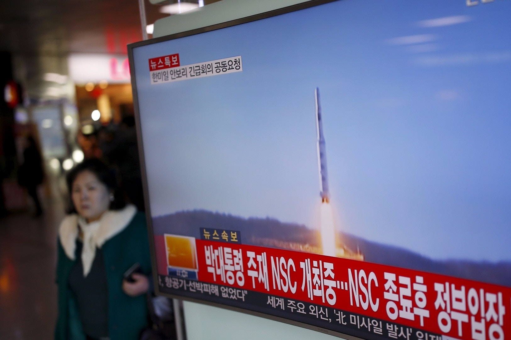 朝鮮今早發射長程火箭，韓國電視台密切報道。圖為首爾火車站電視新聞畫面，播放2012年朝方火箭發射的情況。（路透社）