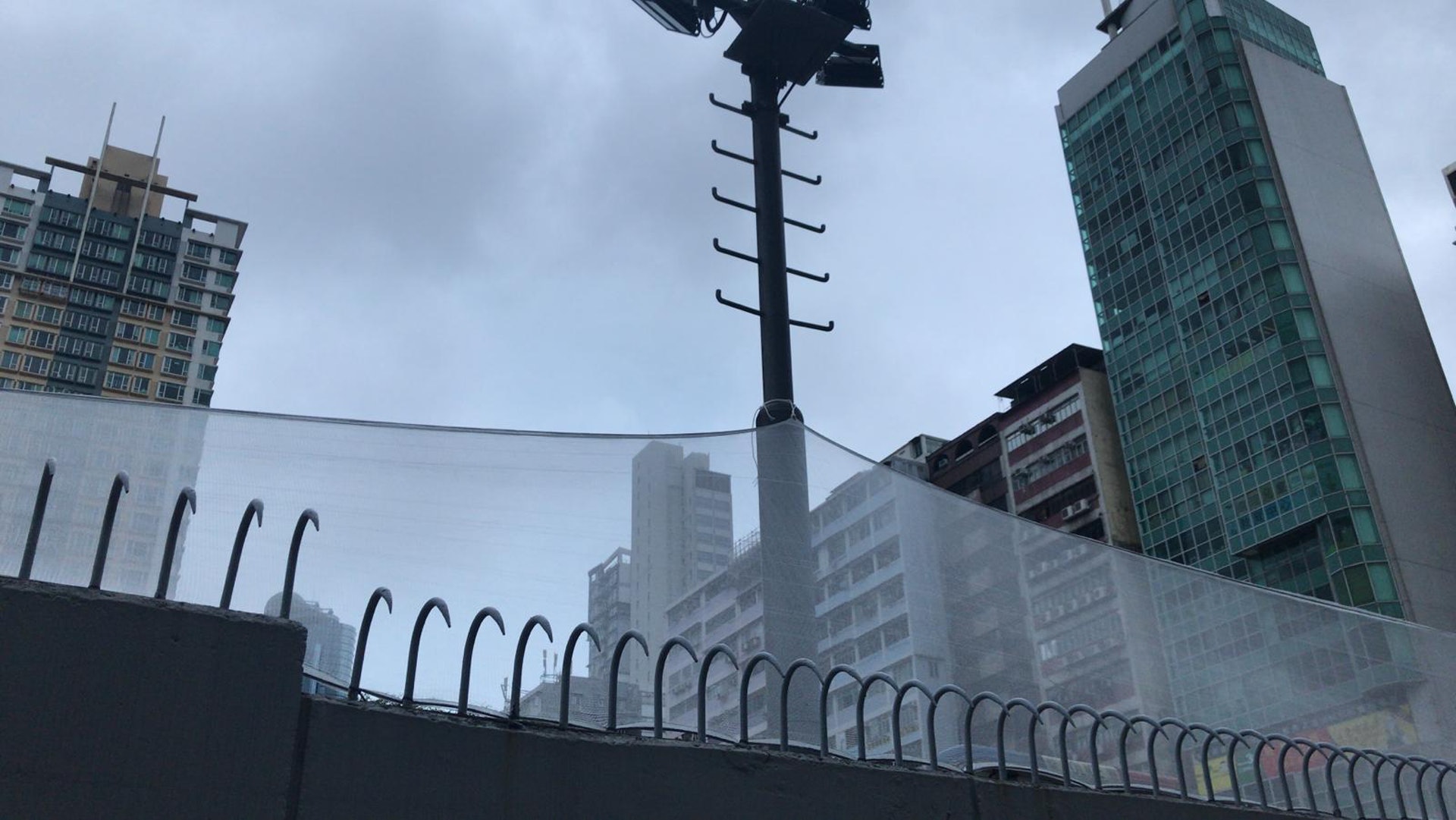 有工人在旺角警署防盜鐵欄加高白紗網。(曾鳳婷攝)