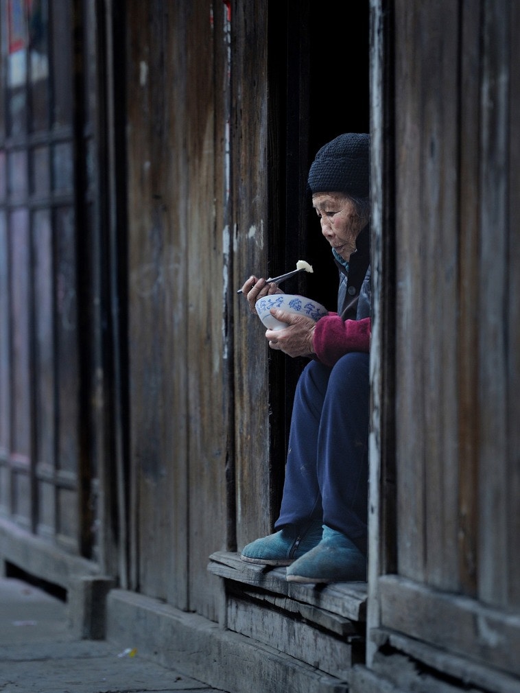 一位老人坐在芙蓉鎮街邊吃飯。（視覺中國）