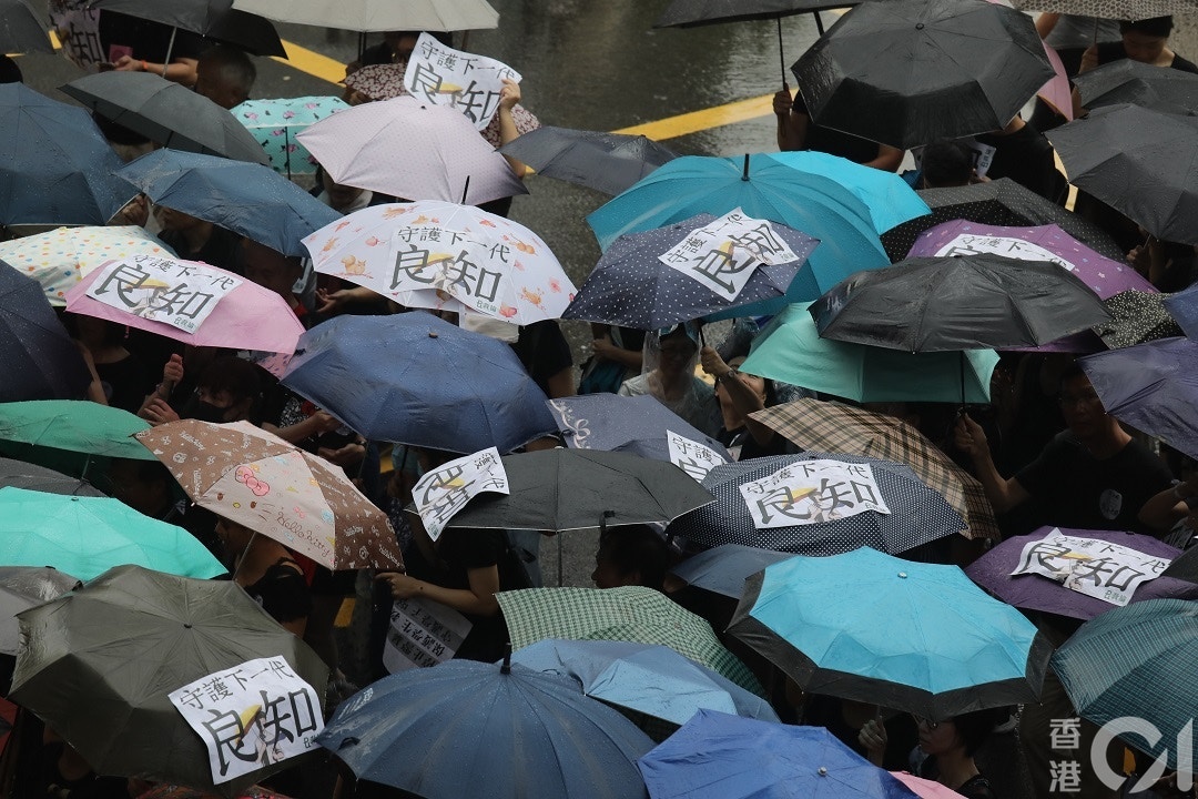 香港教育專業人員協會本月17日發起主題為「守護下一代，為良知發聲」的教育界大遊行。不少老師們在下起大雨時，將標語及訴求貼上雨傘。（資料圖片／林若勤攝）