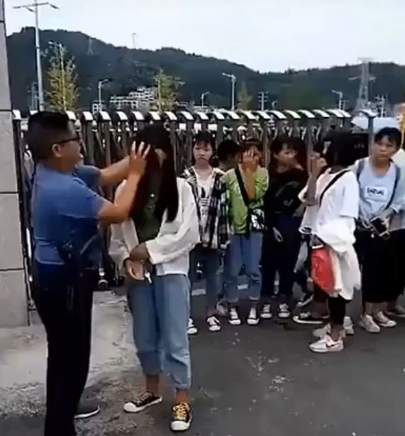 在學校門外，一群帶著行李的女生排著隊，等待這位男教師逐一親自卸妝。（網上圖片）