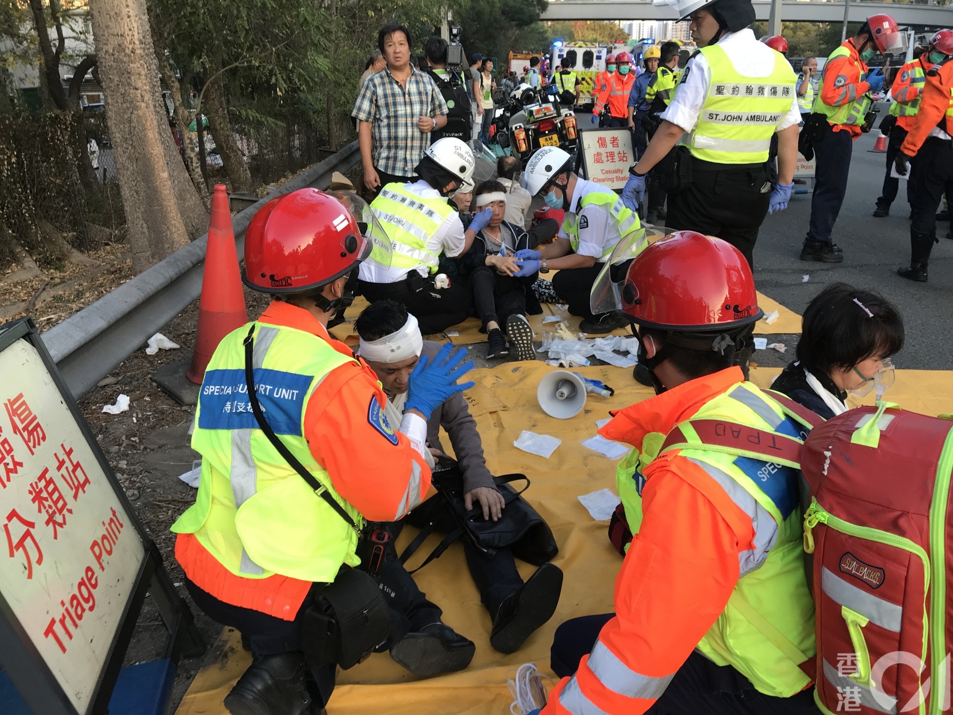 傷者坐在地上由救援人員協助包紮。（黃廸雯攝）