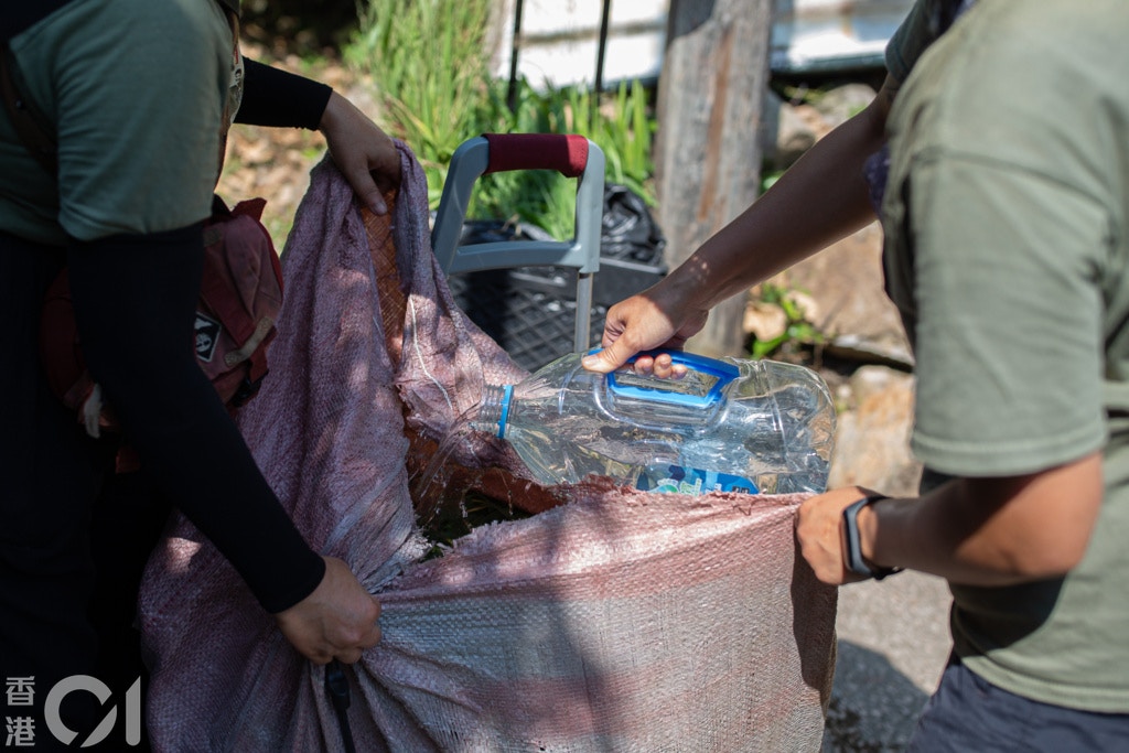 天氣炎熱,義工先用水滋潤帶來的草。(梁鵬威攝) 天氣炎熱,義工先用水滋潤帶來的草。(梁鵬威攝)