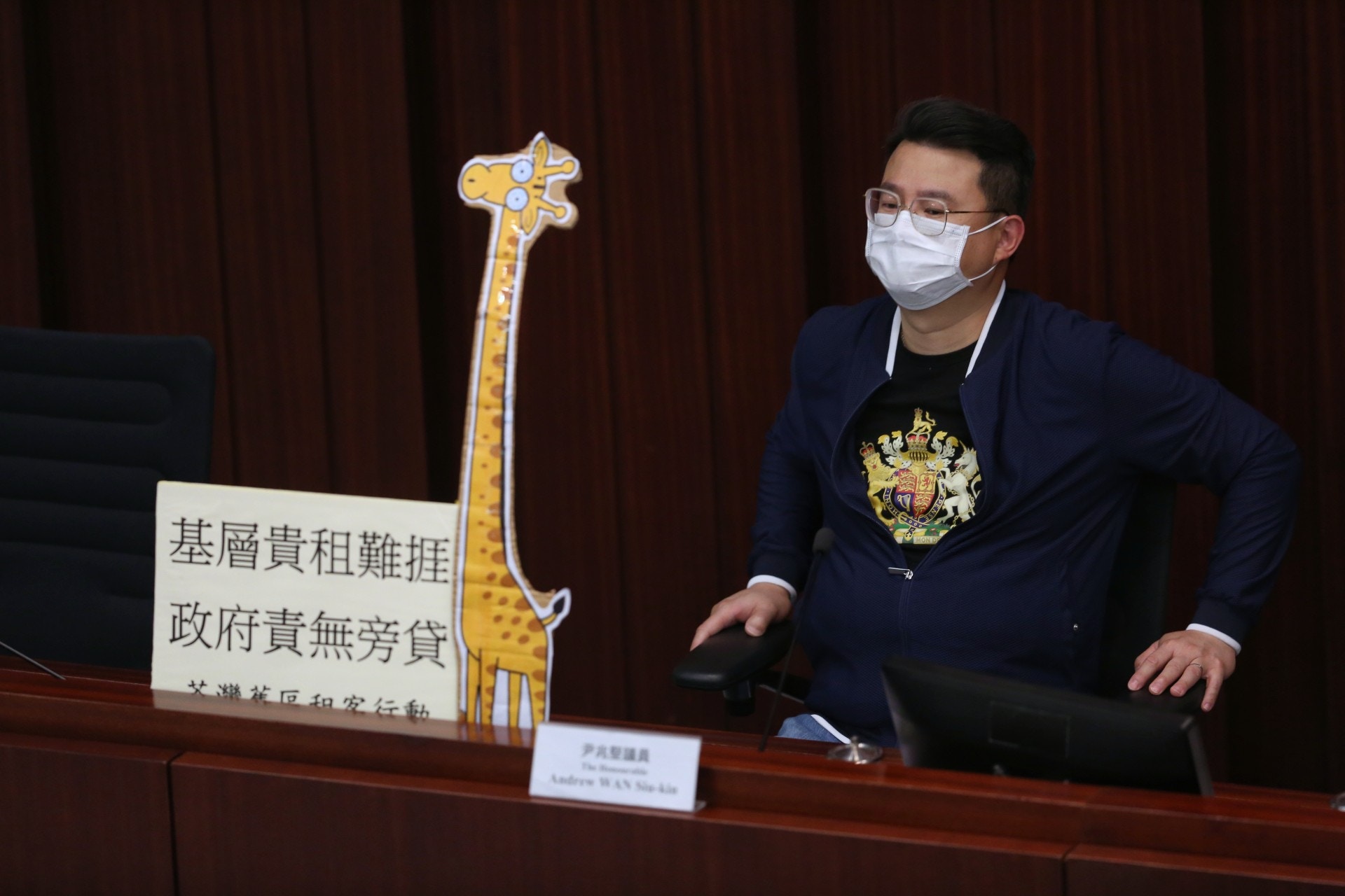 多名議員在會議放上「長頸鹿」紙牌，指民間等待租管「等到頸都長」。（張浩維攝）