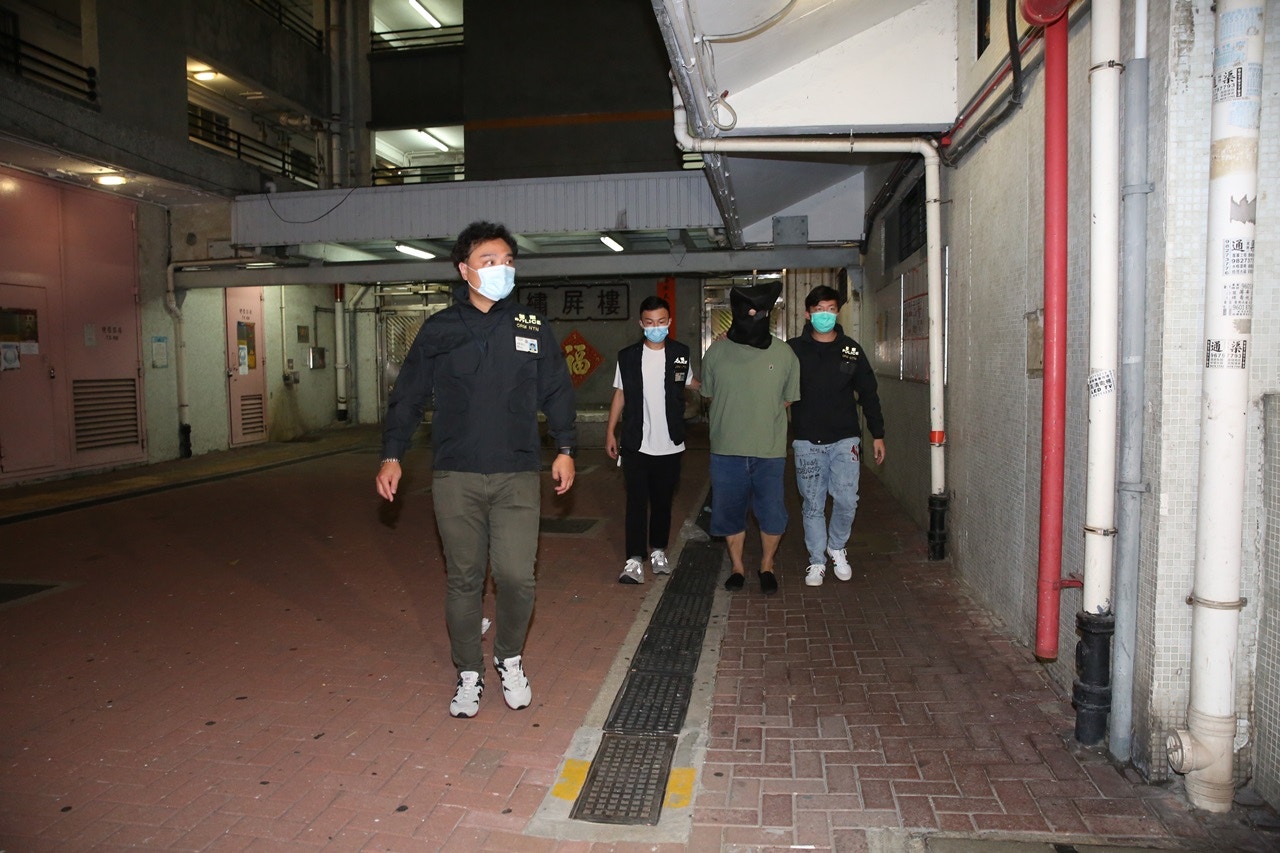 周六（25日）凌晨約零時，被捕男子遭黑布蒙頭，押至元朗朗屏邨繡屏樓搜證，逗留近20分鐘後離開。（陳永武攝）