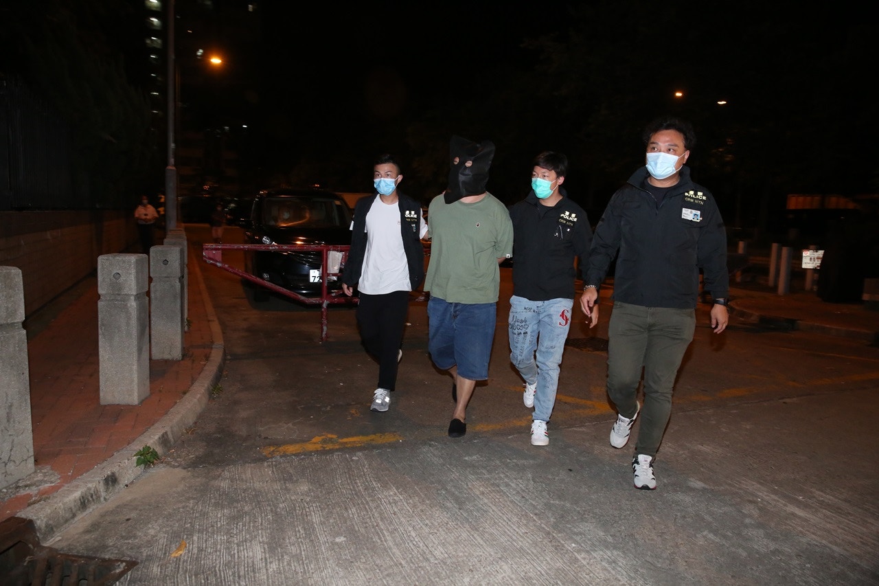 周六（25日）凌晨約零時，被捕男子遭黑布蒙頭，押至元朗朗屏邨繡屏樓搜證。（陳永武攝）