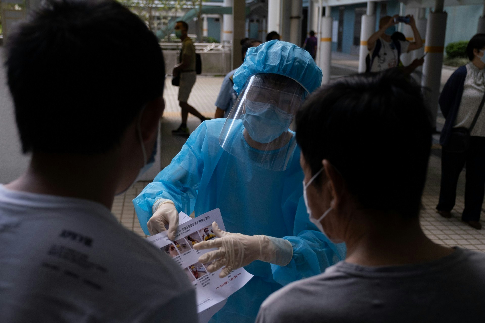 身穿保護衣的人員派發時向市民說明檢測方法,並提醒他們明天交回樣本去收集箱。(梁鵬威攝) 身穿保護衣的人員派發時向市民說明檢測方法,並提醒他們明天交回樣本去收集箱。(梁鵬威攝)