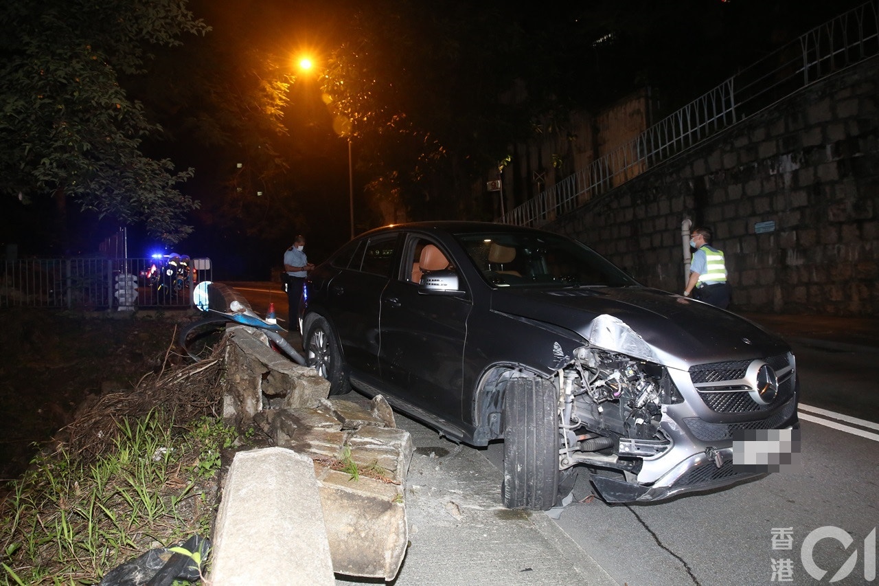 楊明駕車「自炒」，座駕擱上石壆。（陳永武攝）