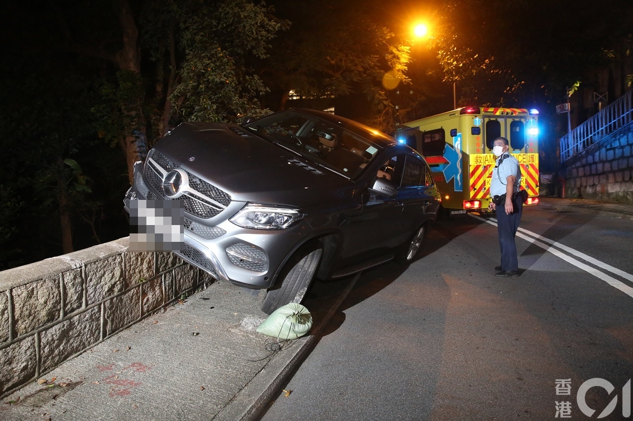 楊明駕車「自炒」，座駕擱上石壆。（陳永武攝）