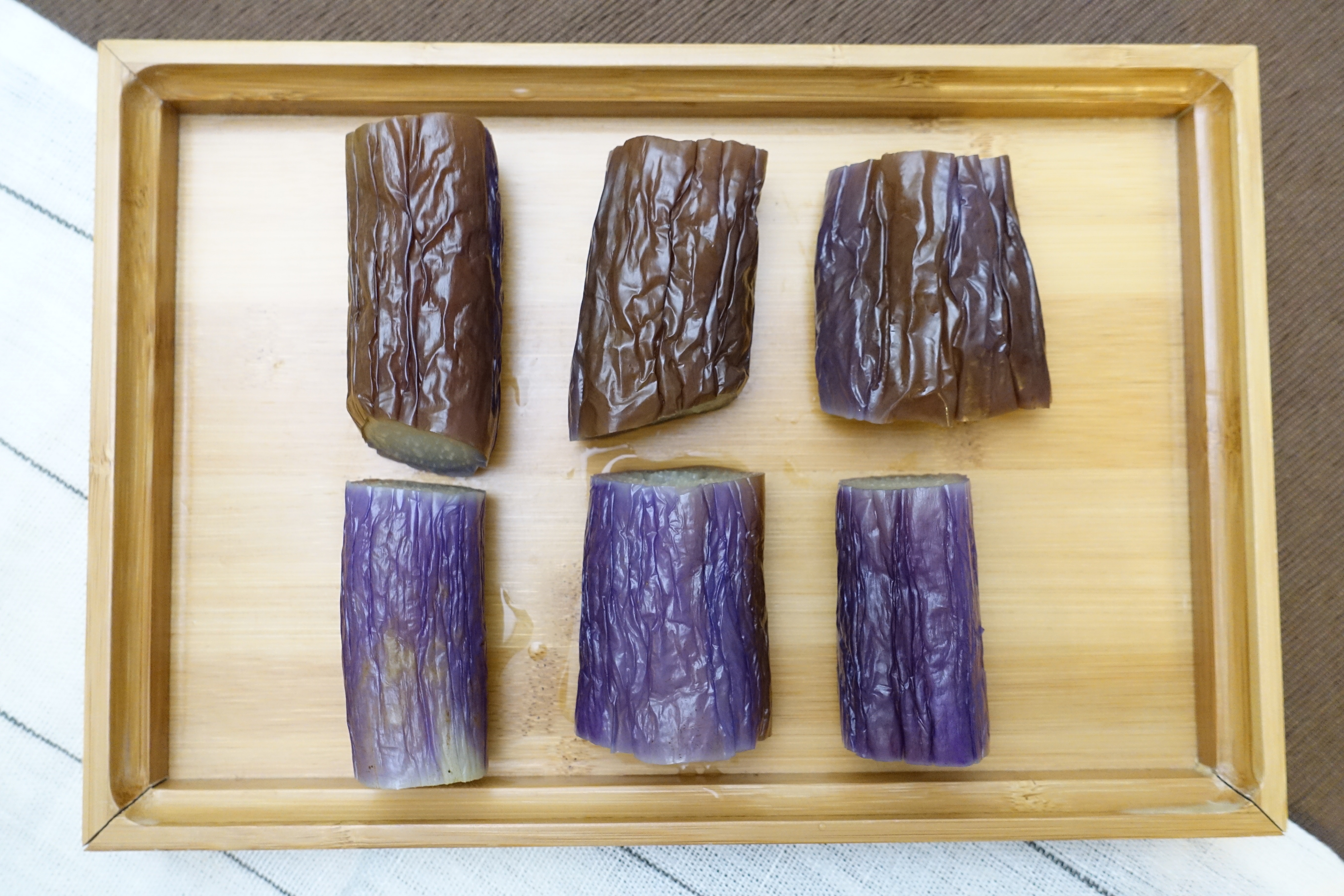 烚茄子一般會浮上水面，茄子皮易變色（上），用碟壓着（下）紫色皮的色彩仍在。（鄒家鳳攝）