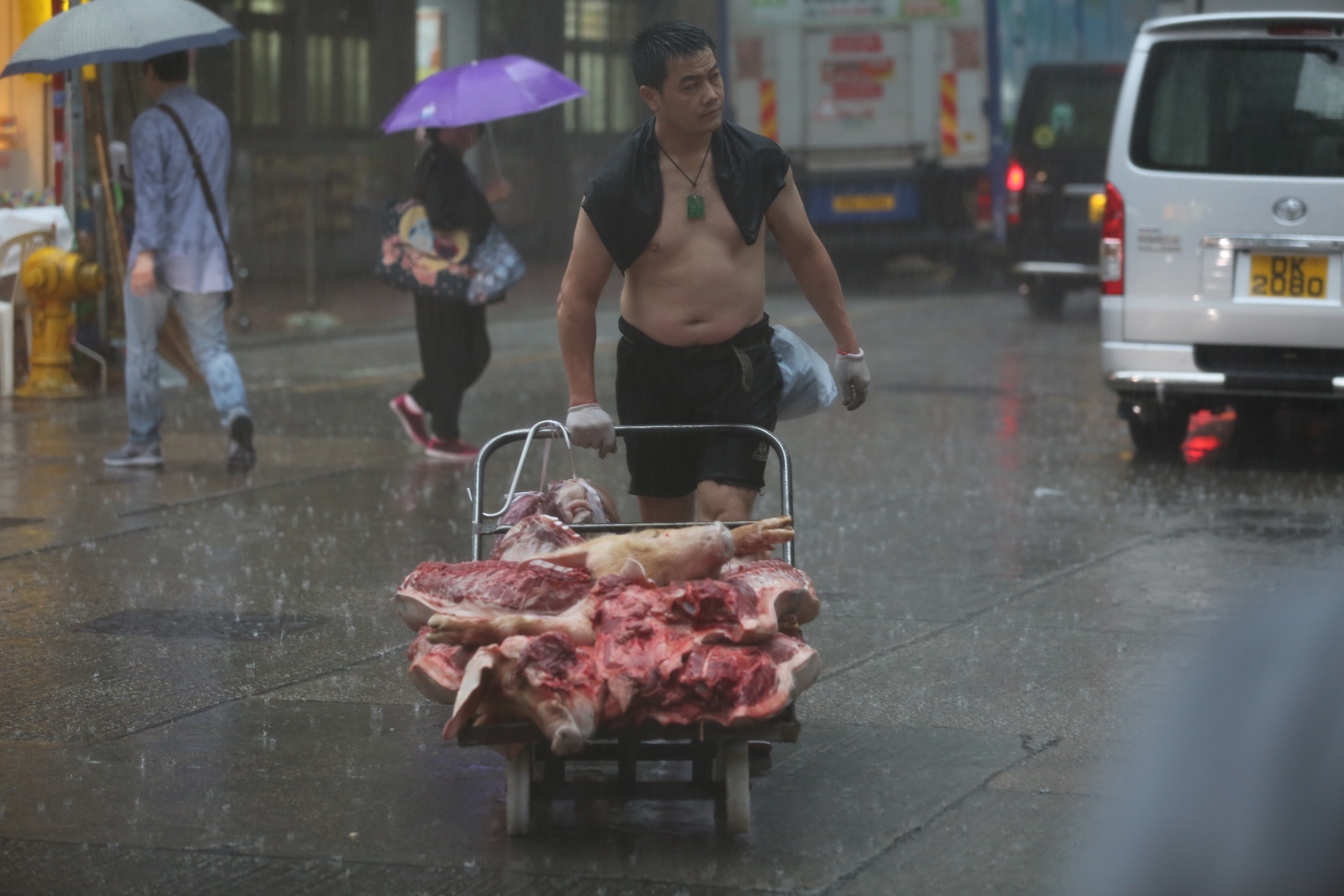 佐敦有豬肉佬不帶任何雨具，散發一身霸氣送豬肉。（蔡正邦攝）