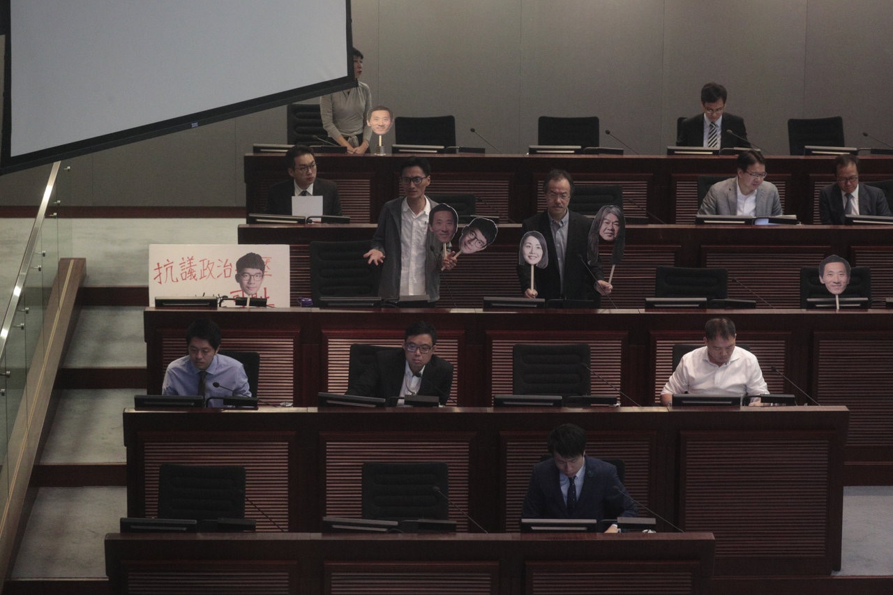 泛民議員在座位上展示梁國雄、劉小麗、羅冠聰及姚松炎的面具，以展不滿四人被取消議員資格。（鍾偉德攝）