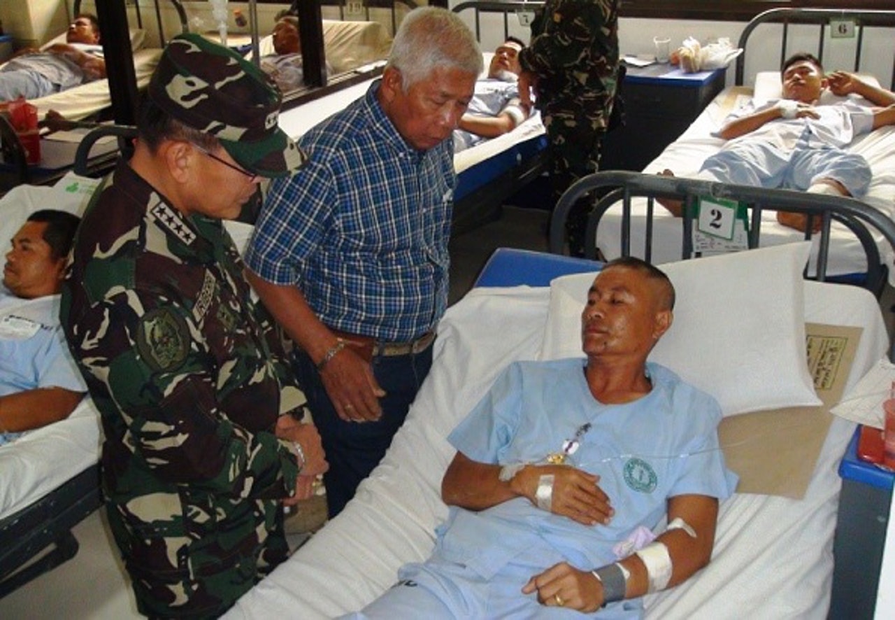 菲律賓國防部長Voltaire Gazmin(中)及軍方總司令Hernando Iriberri (左)於事後探望受傷的士兵。(Getty Images) 菲律賓國防部長Voltaire Gazmin(中)及軍方總司令Hernando Iriberri (左)於事後探望受傷的士兵。(Getty Images)