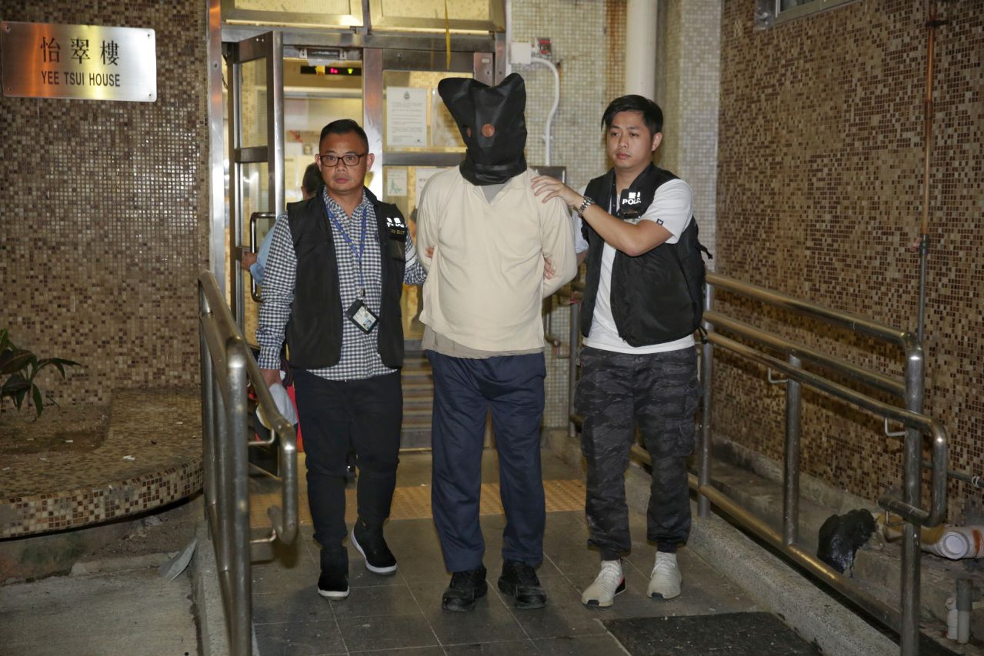 警員晚上將疑犯押返柴灣住所搜查。(黃偉民攝) 警員晚上將疑犯押返柴灣住所搜查。(黃偉民攝)