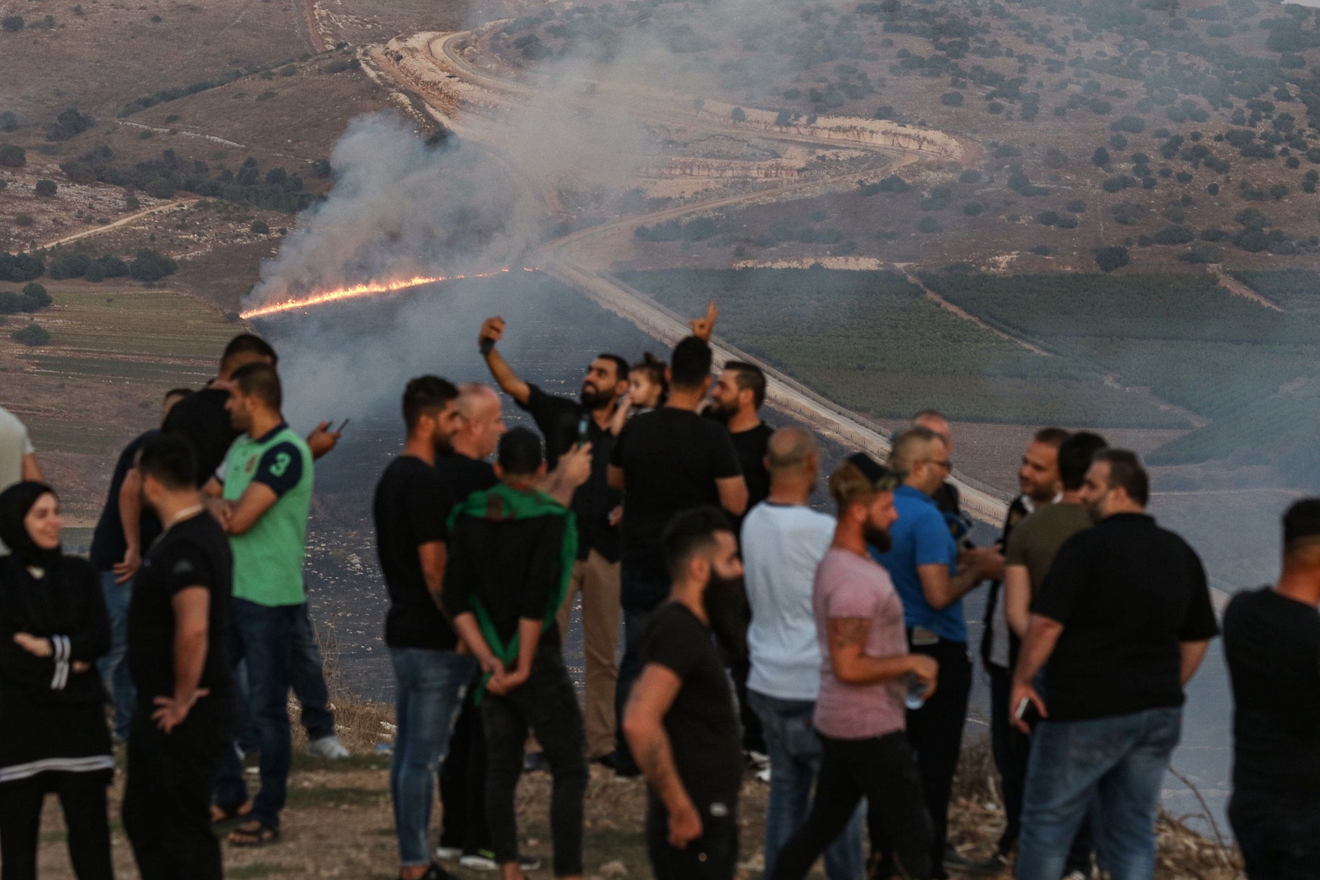 黎巴嫩以色列衝突:人們9月1日在高處擺出勝利姿勢,與被濃煙籠罩的黎巴嫩村莊邁龍角(Maroun al-Ras)合照。(VCG)