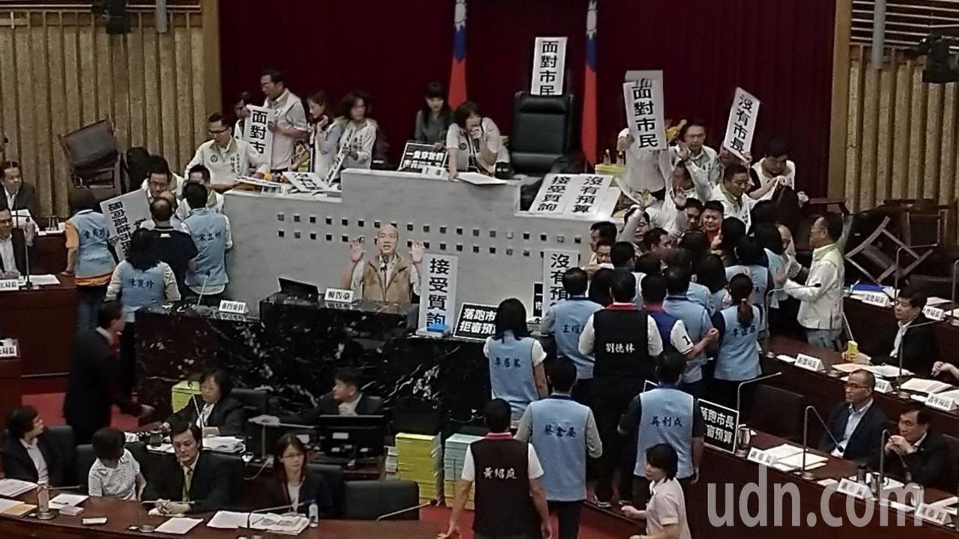 民進黨籍議員拒絕在市長韓國瑜不在場的情況下審議,遂提前約半小時就帶同道具霸佔主席台。(聯合新聞網) 民進黨籍議員拒絕在市長韓國瑜不在場的情況下審議,遂提前約半小時就帶同道具霸佔主席台。(聯合新聞網)