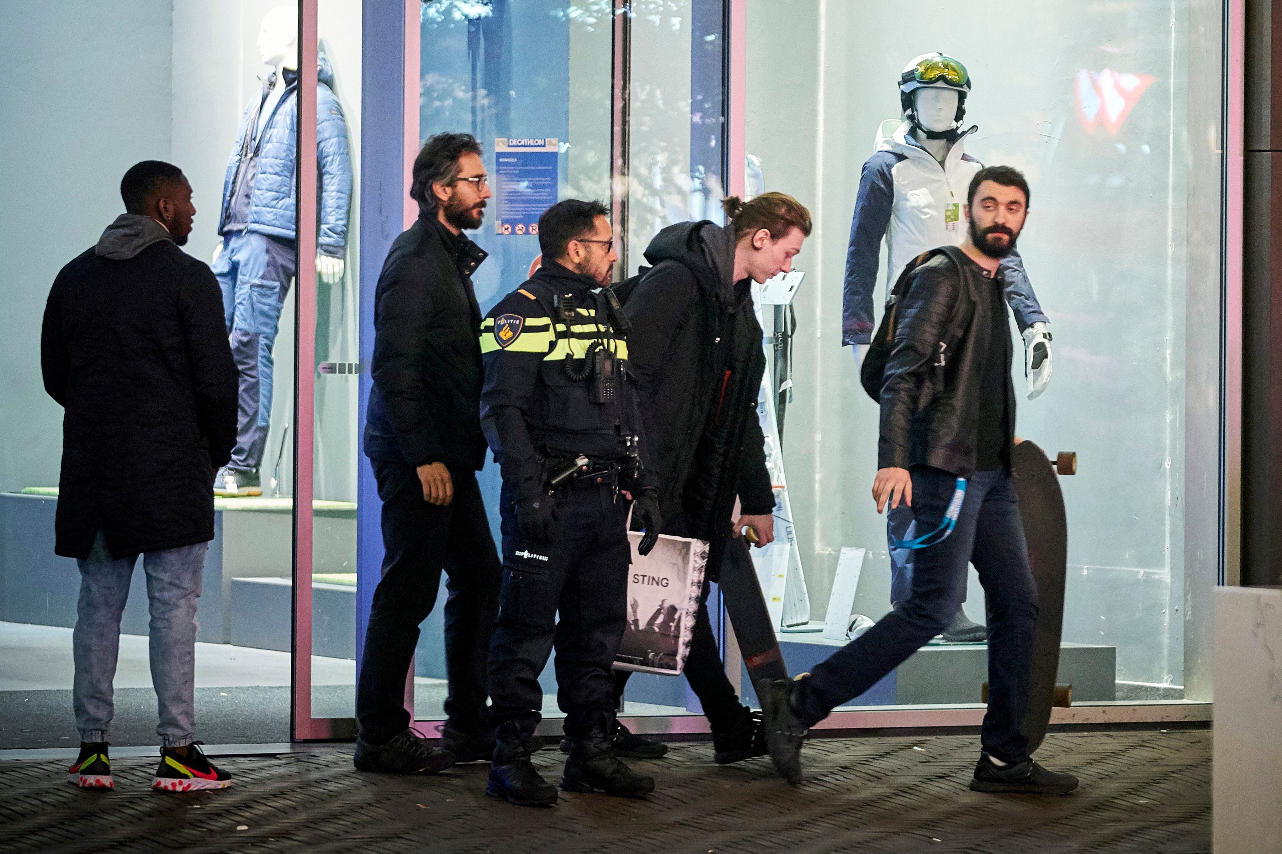 荷蘭海牙持刀襲擊案:案發時,有不少民眾在現場購物。圖為11月29日,市民在警方設置封鎖線後離開店鋪。(AP)