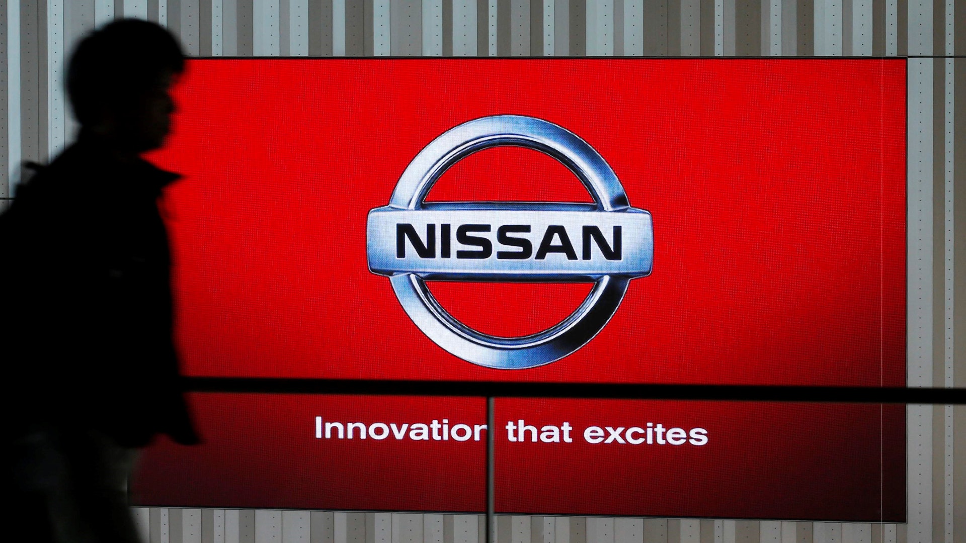 戈恩接手日產後很快扭轉虧損局面。圖為當地時間2014年12月18日一名男子走過日產在日本橫濱的展台。(路透社) 戈恩接手日產後很快扭轉虧損局面。圖為當地時間2014年12月18日一名男子走過日產在日本橫濱的展台。(路透社)