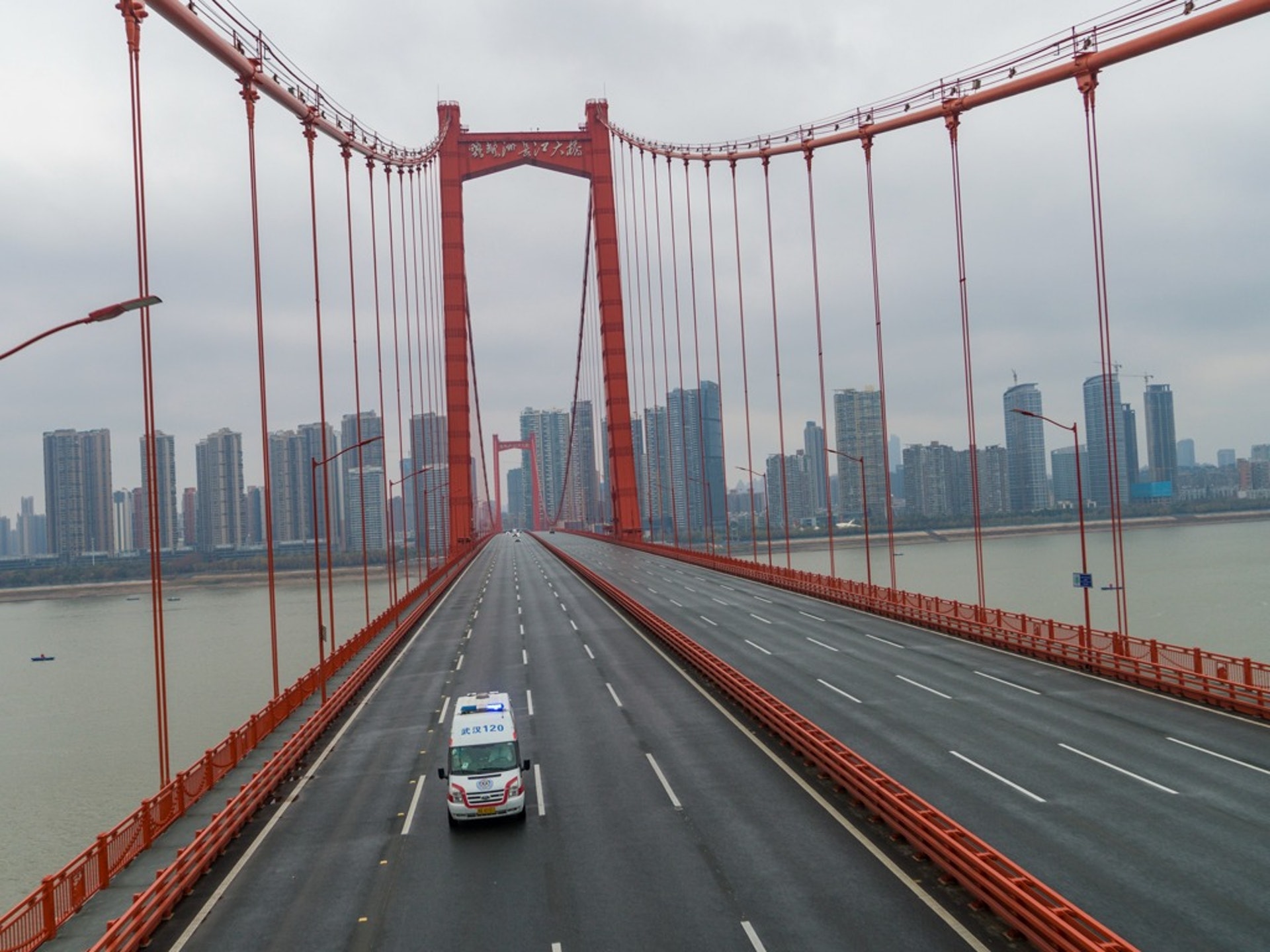 2020年1月25日,一輛救護車駛過武漢市一座幾乎空無一人的大橋。(AP)