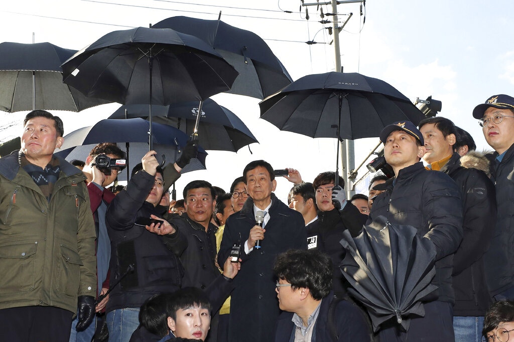 韓國官員落區解釋「隔離營」計劃，警員在旁出動「傘陣」護航，以擋下民眾投擲的雞蛋（美聯社）