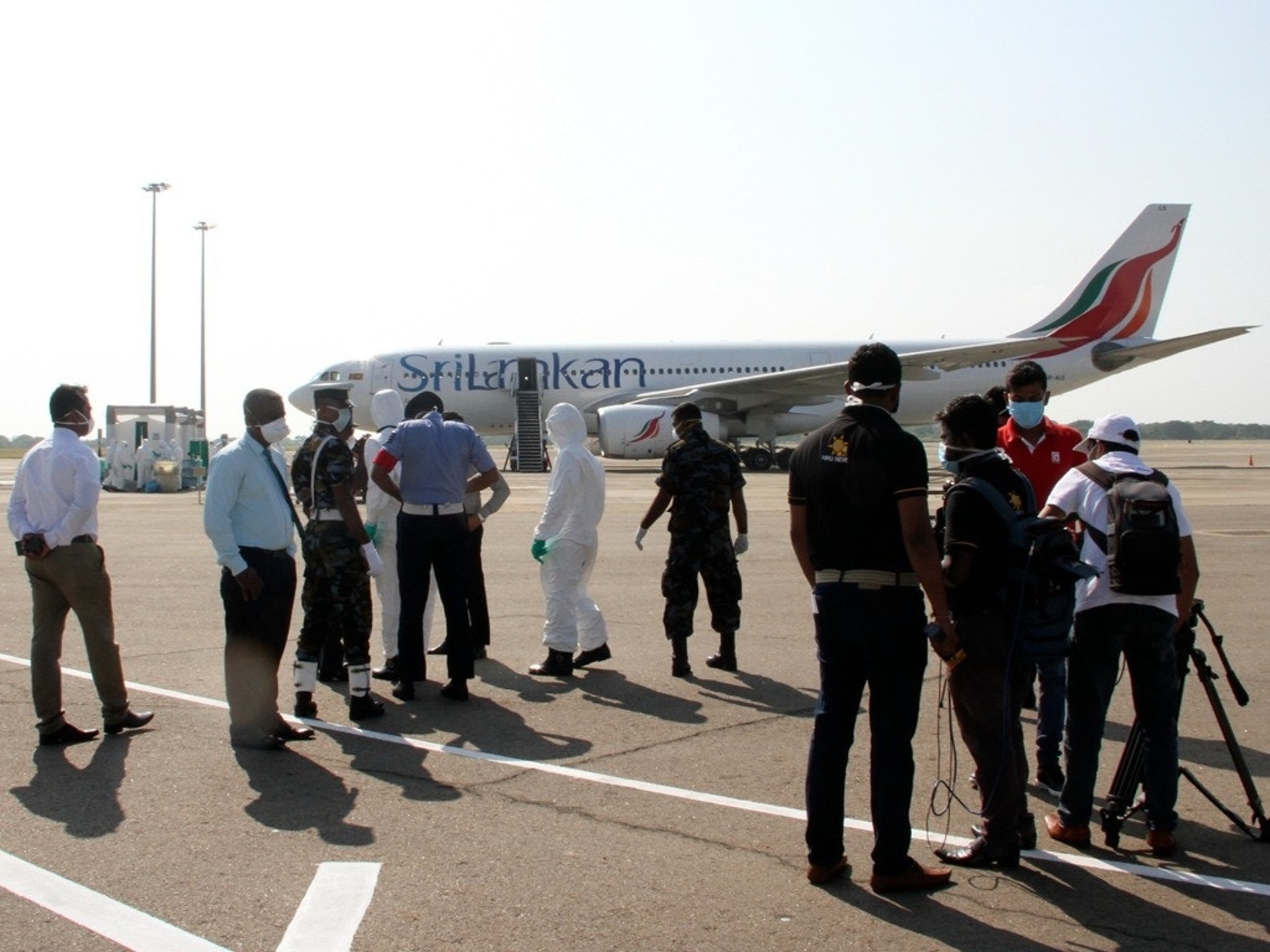 由于疫情不断恶化，多个国家已经开始撤离在武汉的侨民。图为一架从中国武汉撤离的斯里兰卡学生乘坐的客机降落在斯里兰卡马塔拉的马欣达·拉贾帕克萨国际机场，斯里兰卡医护人员身着防护服，正在进行消毒。（AP）