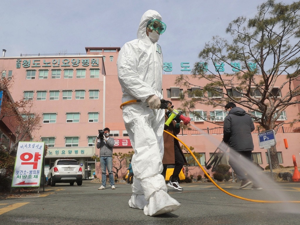 2020年2月21日，一名穿戴防護裝備的工作人員在韓國清道大南醫院大門外噴灑消毒劑。（AP）
