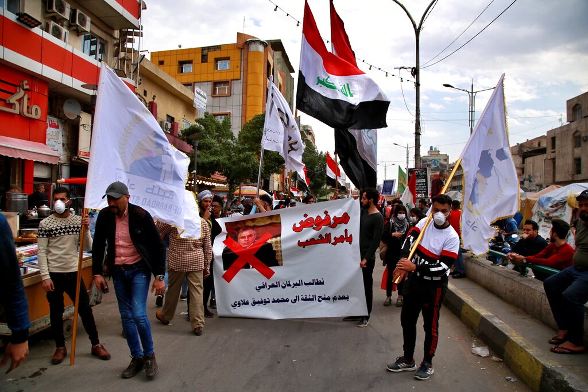 伊拉克的示威者想推翻政府精英管治,也認為候任總理阿拉維是他們一分子,反對他上任。圖為3月1日伊拉克首都巴格達的示威者舉起海報上街遊行。海報上面印有阿拉維的照片,以及「人民下令拒絕」的字樣。它的意思應是指民眾拒絕讓阿拉維擔任總理。(AP) 伊拉克的示威者想推翻政府精英管治,也認為候任總理阿拉維是他們一分子,反對他上任。圖為3月1日伊拉克首都巴格達的示威者舉起海報上街遊行。海報上面印有阿拉維的照片,以及「人民下令拒絕」的字樣。它的意思應是指民眾拒絕讓阿拉維擔任總理。(AP)