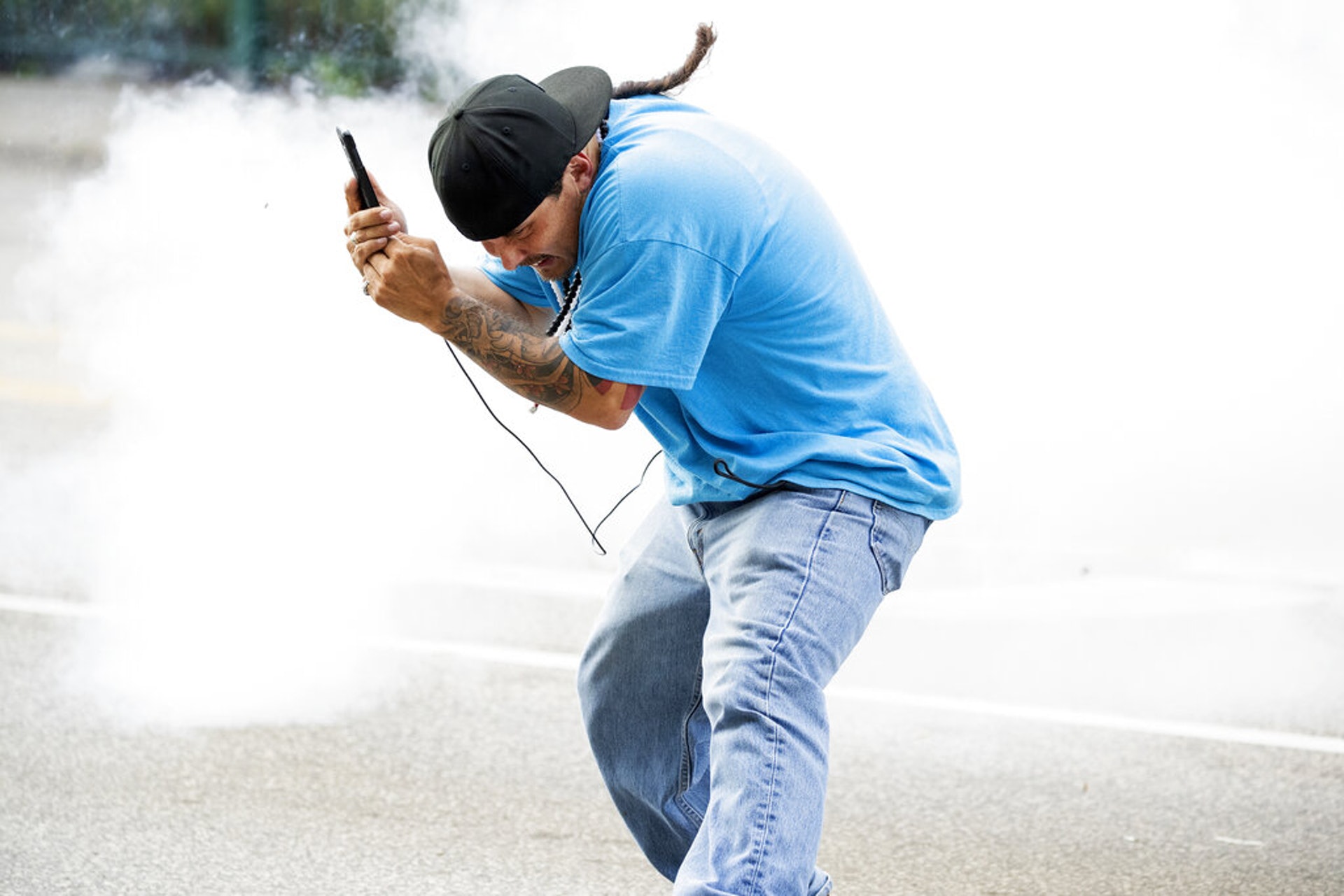 美國黑人喬治・佛洛伊德之死:圖為5月27日明尼阿波利斯市的示威者在該市警察部第三轄區建築物外作勢躲避。(AP)