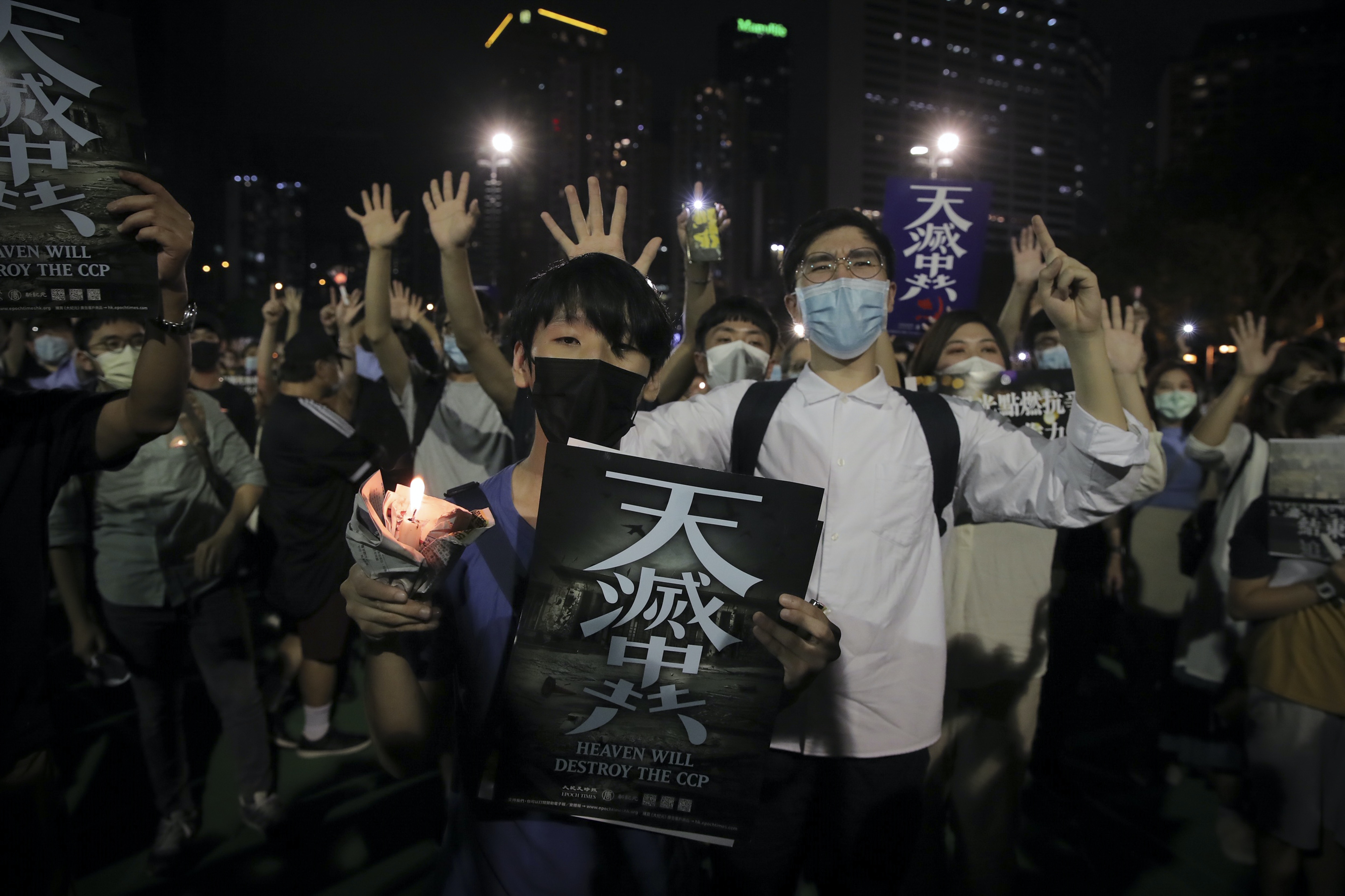 六四31：圖為6月4日，香港大批市民在限聚令下依然前往維園出席六四晚會，有人做出「五大訴求缺一不可」的手勢，也有人高舉寫有「天滅中共」的海報。（AP）