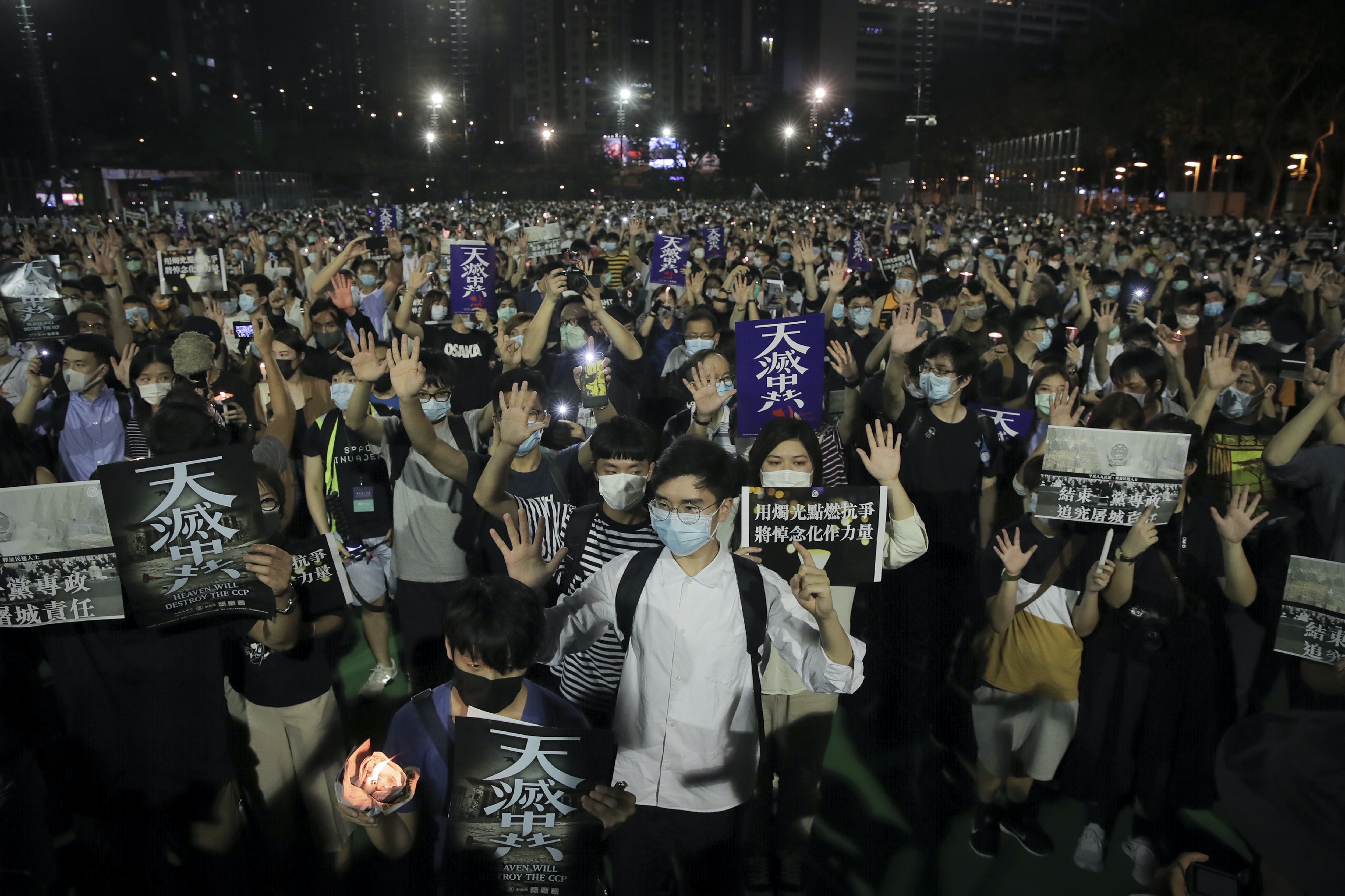 六四31：圖為6月4日，香港大批市民在限聚令下依然前往維園出席六四晚會，有人做出「五大訴求缺一不可」的手勢，也有人高舉寫有「天滅中共」的海報。（AP）