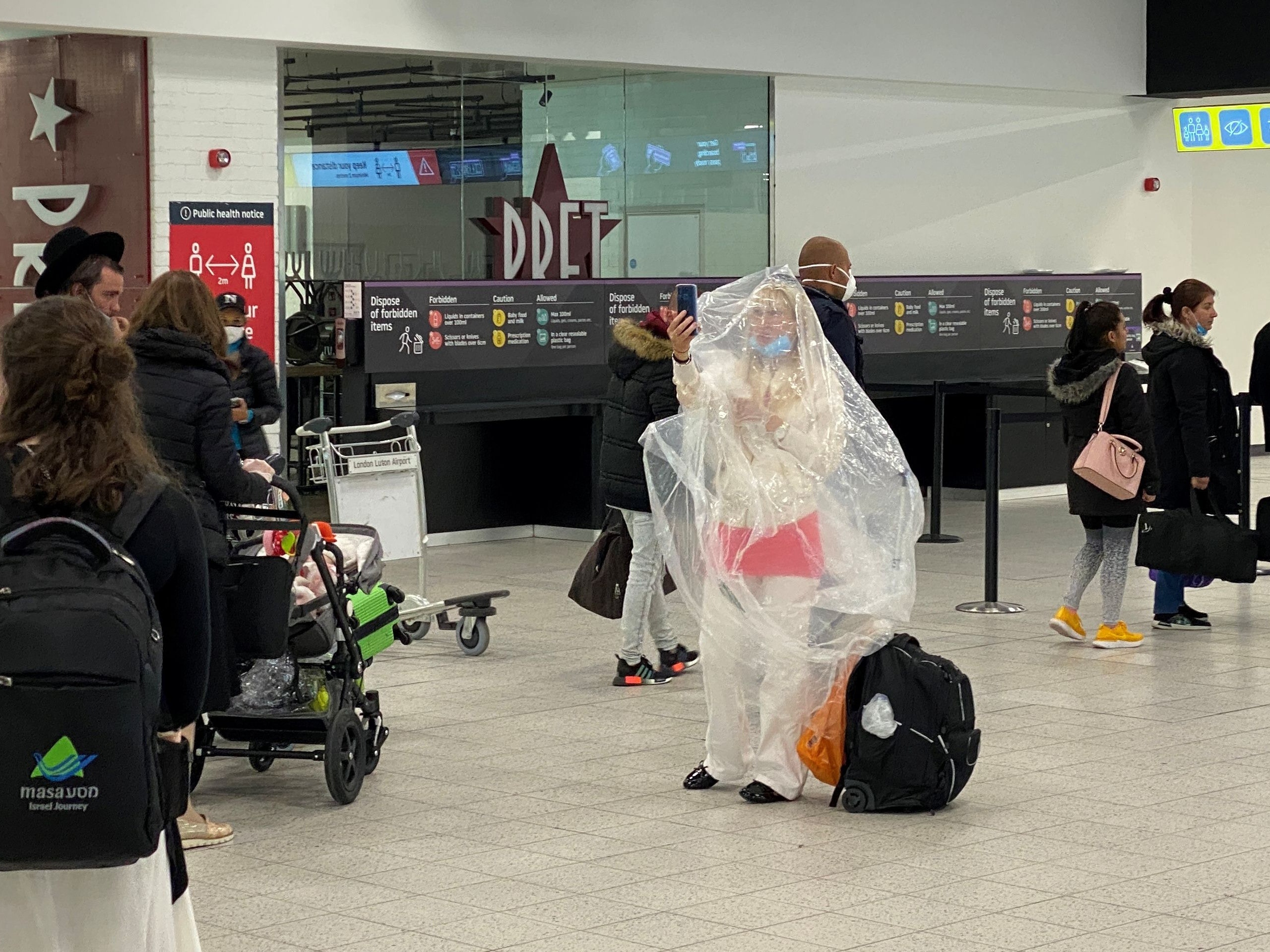 入境英國的旅客將要自我隔離14日。圖為6月4日，英國倫敦盧頓機場（Luton Airport ）乘客穿上防疫裝備的情況。（Reuters）