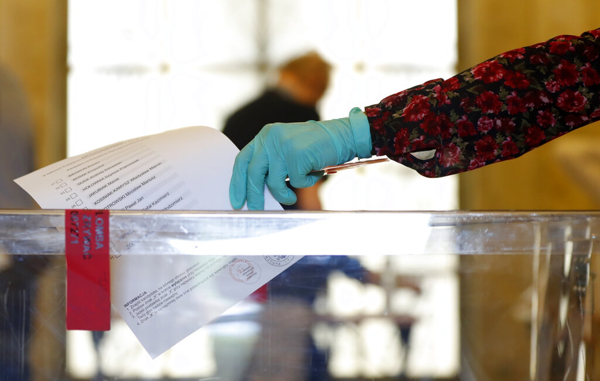 波蘭大選:華沙一名居民6月28日到投票站投票,期間戴着防護手套。(AP)