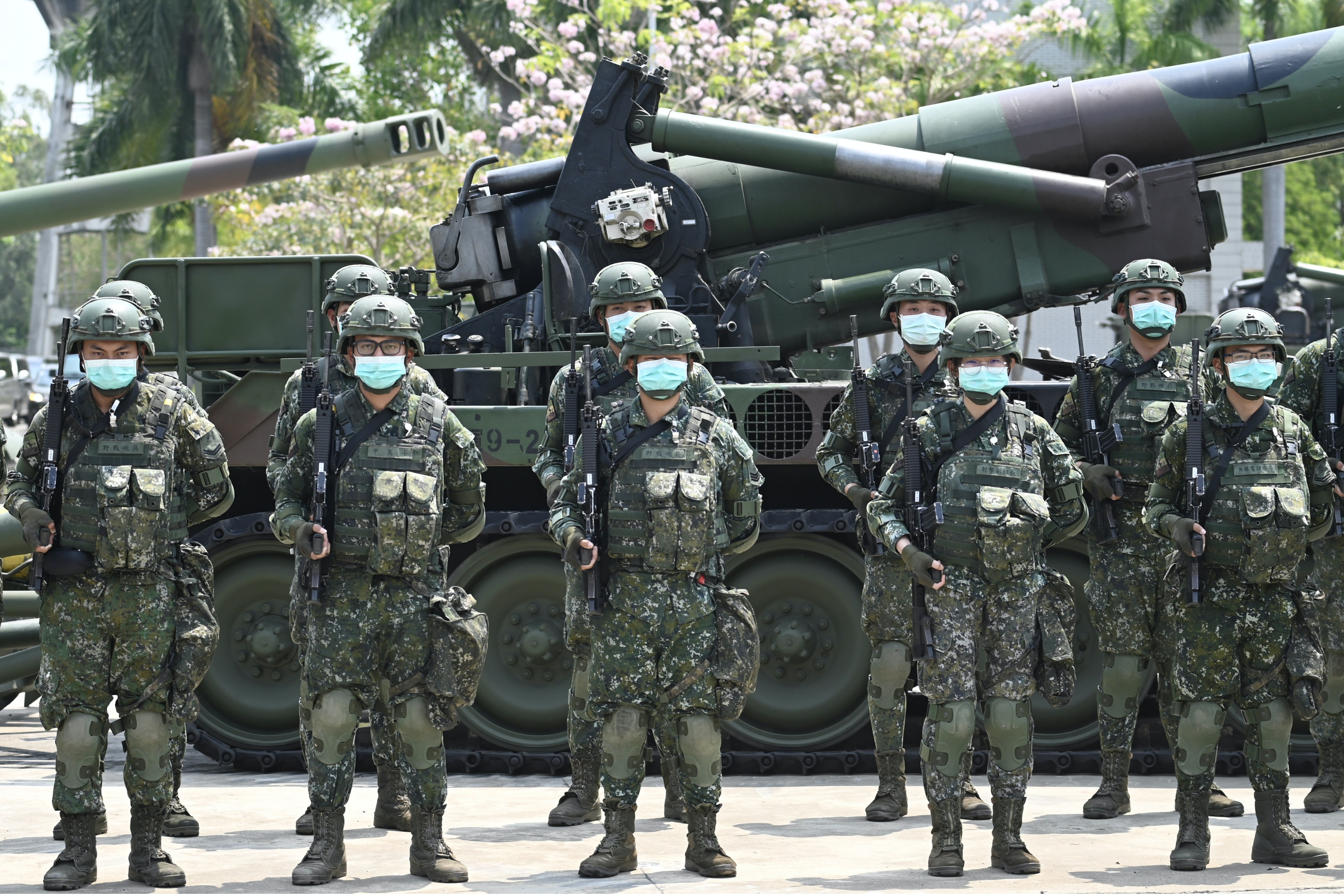 Soldiers wearing face masks amid the COVID-19 coronavirus pandemic stand in formation in front of a US-made M110A2 self-propelled howitzer during Taiwan President Tsai Ing-wen's visit to a military base in Tainan, southern Taiwan, on April 9, 2020. - Taiwan currently has just 375 confirmed Covid-19 patients and five deaths …