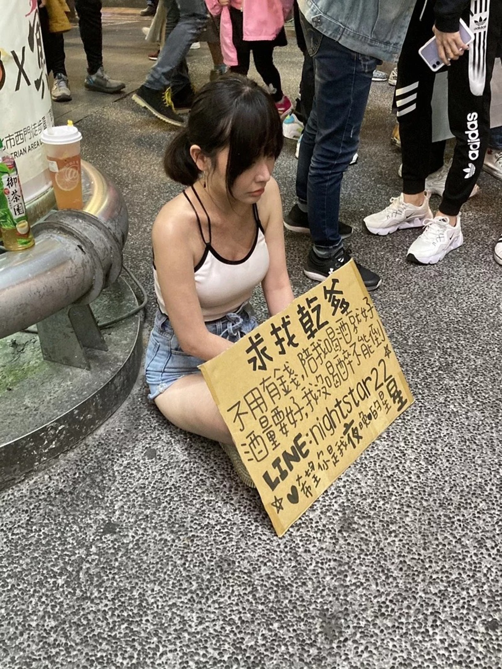 一名正妹坐在西門町,身前掛著「求找乾爹」厚紙板,引發網路及路過民眾的關注。(聯合新聞網提供) 一名正妹坐在西門町,身前掛著「求找乾爹」厚紙板,引發網路及路過民眾的關注。(聯合新聞網提供)