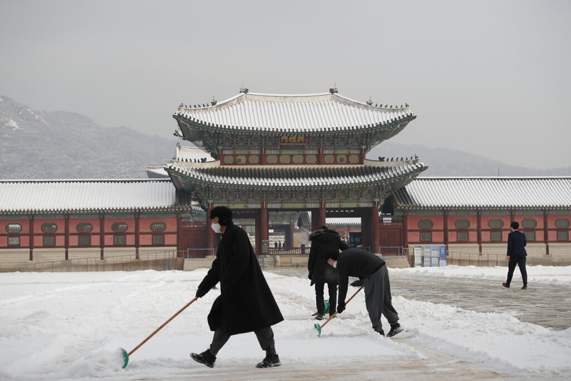 新冠肺炎疫情：圖為1月13日在韓國首爾，工作人員在清除景福宮的積雪。（AP）